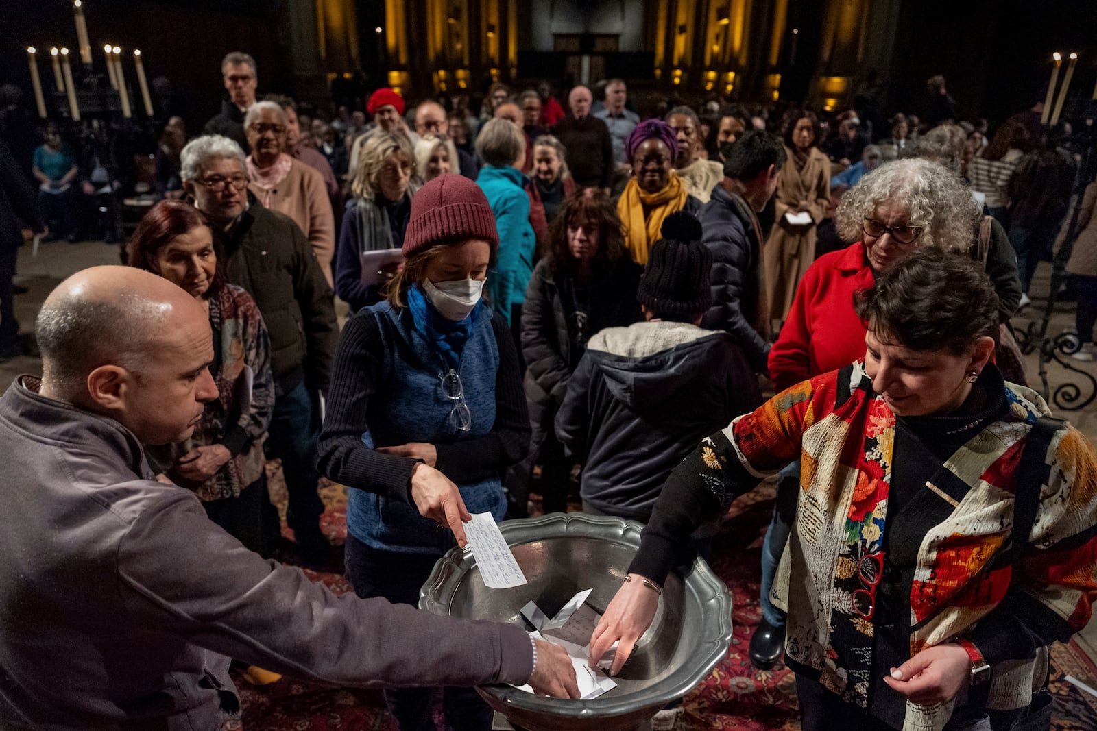 People place papers with their fears written down into a basin during an interfaith vigil for sanctuary at the Cathedral Church of St. John the Divine, Wednesday, Feb. 12, 2025, in New York. (AP Photo/Julia Demaree Nikhinson)