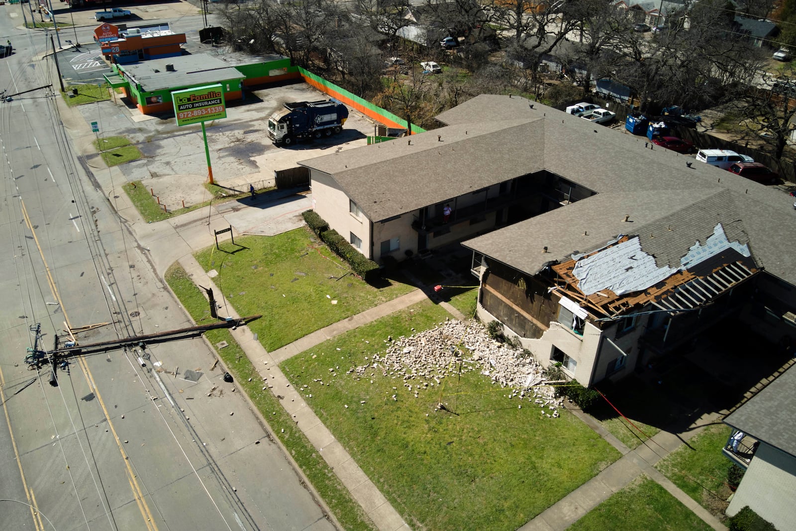 A downed power line rests on the road near an apartment building damaged during early morning storm that hit the Dallas region Tuesday, March 4, 2025, in Irving, Texas. (AP Photo/Julio Cortez)