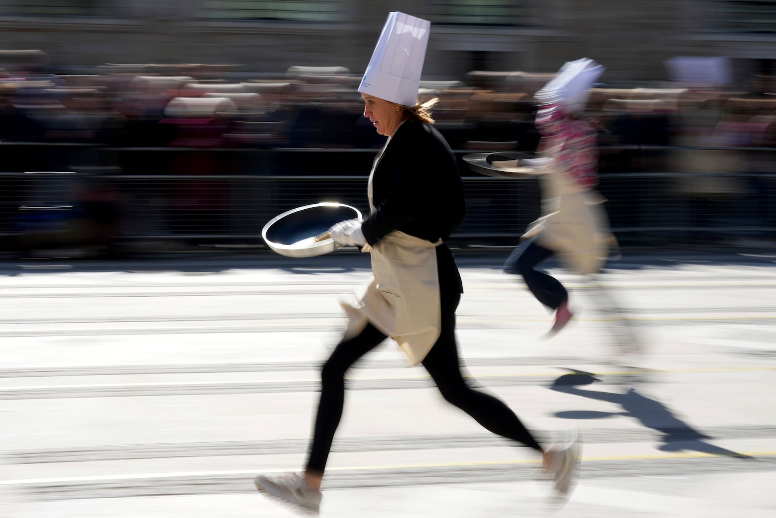 Runners compete during a traditional pancake race by livery companies at the Guildhall in London, Tuesday, March 4, 2025.(AP Photo/Frank Augstein)