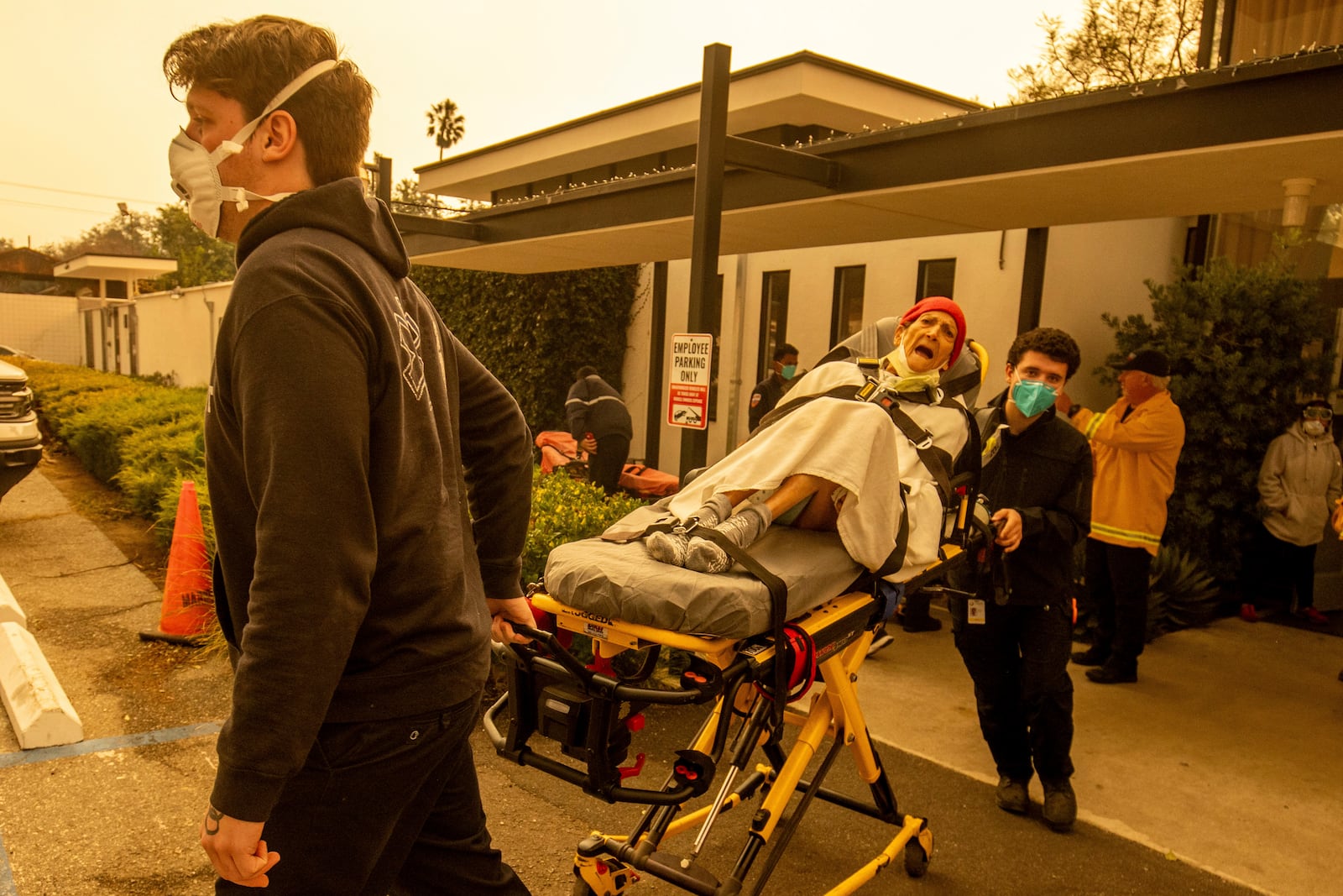 A resident is evacuated from a senior living facility as the Eaton Fire approaches Wednesday, Jan. 8, 2025 in Altadena, Calif. (AP Photo/Ethan Swope)