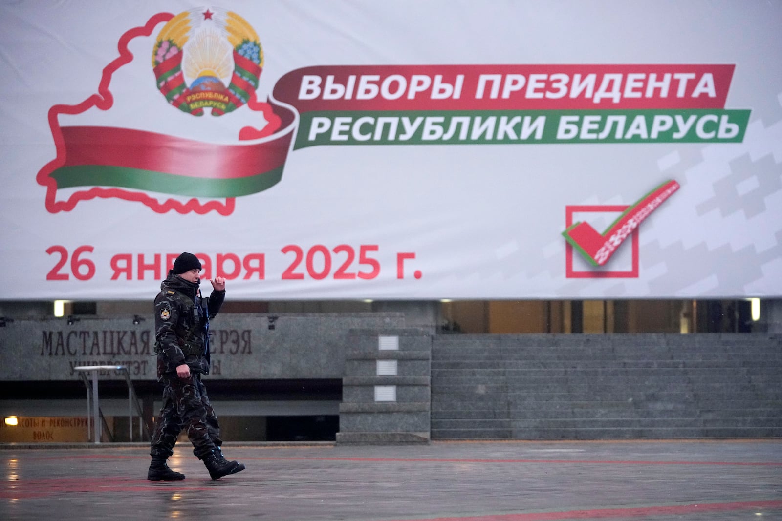 A police officer walks past an election billboard ahead of presidential elections in Minsk, Belarus, Friday, Jan. 24, 2025. (AP Photo/Pavel Bednyakov)