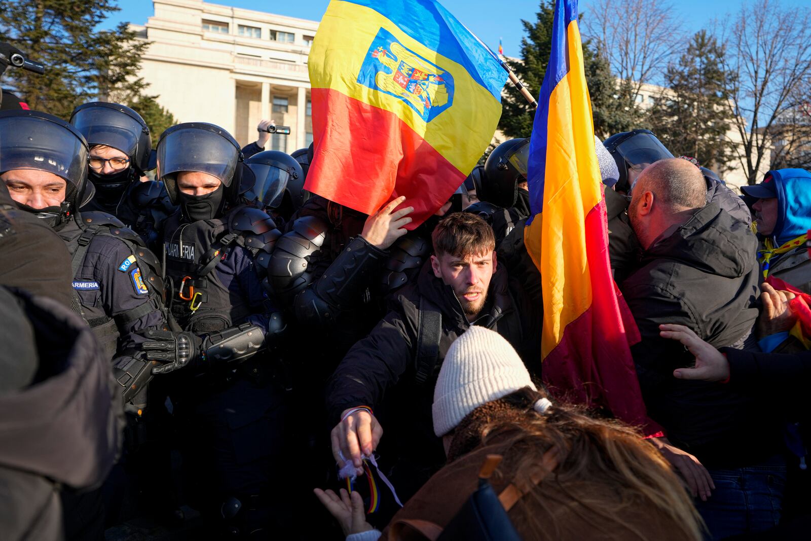 Riot police scuffle with supporters of Calin Georgescu, the winner of Romania's first round of presidential election which the Constitutional Court later annulled, who broke through police lines in front of the government headquarters, in Bucharest, Romania, Monday, Feb. 10, 2025. (AP Photo/Vadim Ghirda)