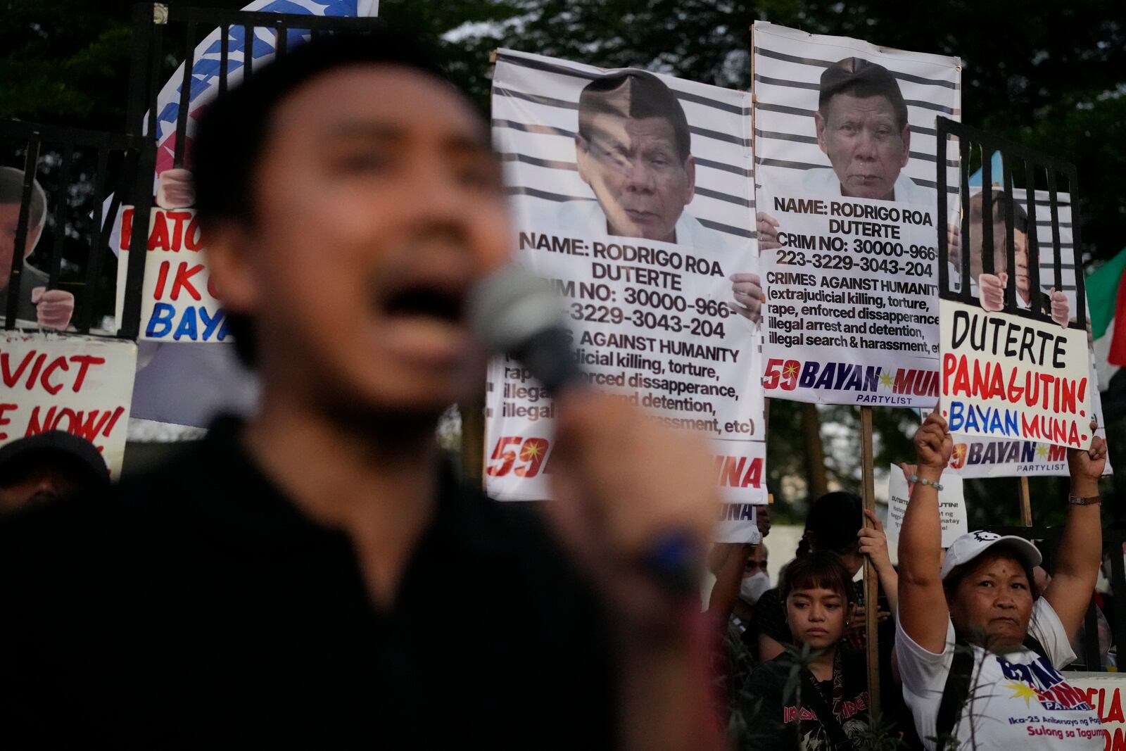 A protester speaks in front of pictures of former President Rodrigo Duterte's as they call for justice to victims of the war on drugs during his administration in Quezon city, Philippines on Friday, March 14, 2025. (AP Photo/Aaron Favila)