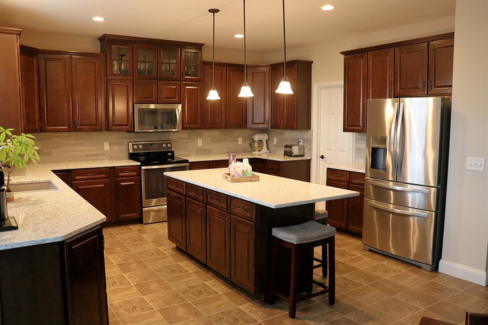 Open from the great room and separated by flooring treatment, the kitchen features three walls of cabinetry with quartz counters.