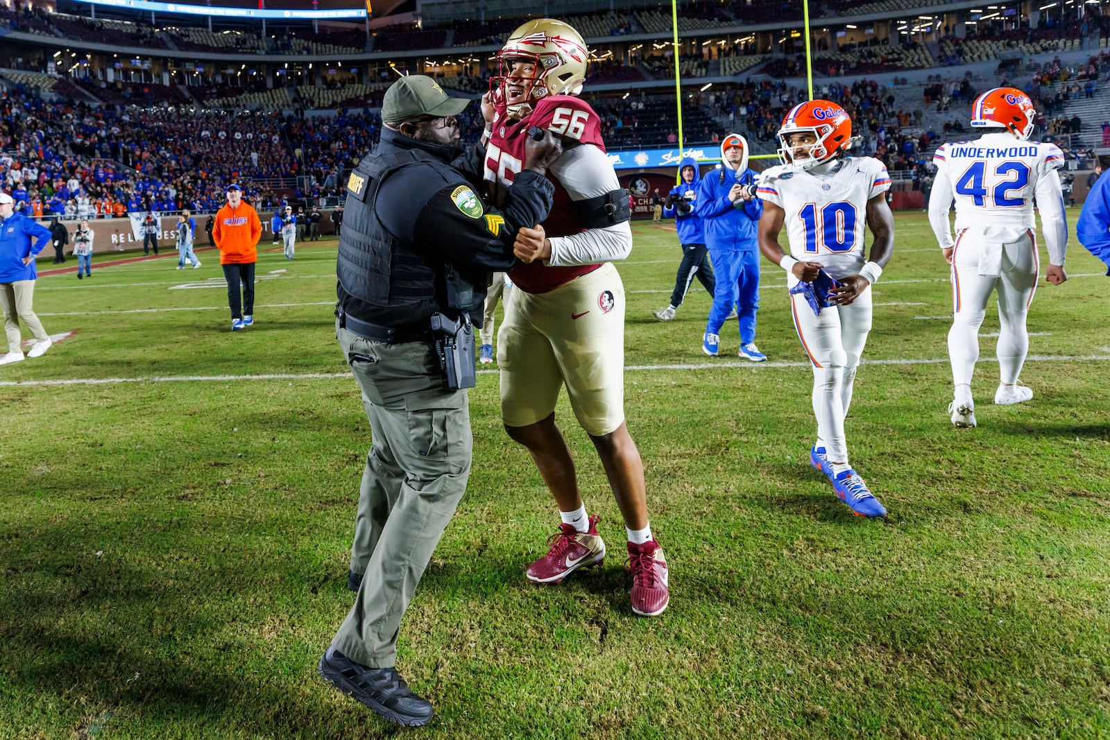 A Leon County Sheriff's Deputy stops Florida State offensive lineman Tye Hylton (56) from engaging with Florida players after the close an NCAA college football game Saturday, Nov. 30, 2024, in Tallahassee, Fla. Florida defeated Florida State 31-11. (AP Photo/Colin Hackley)