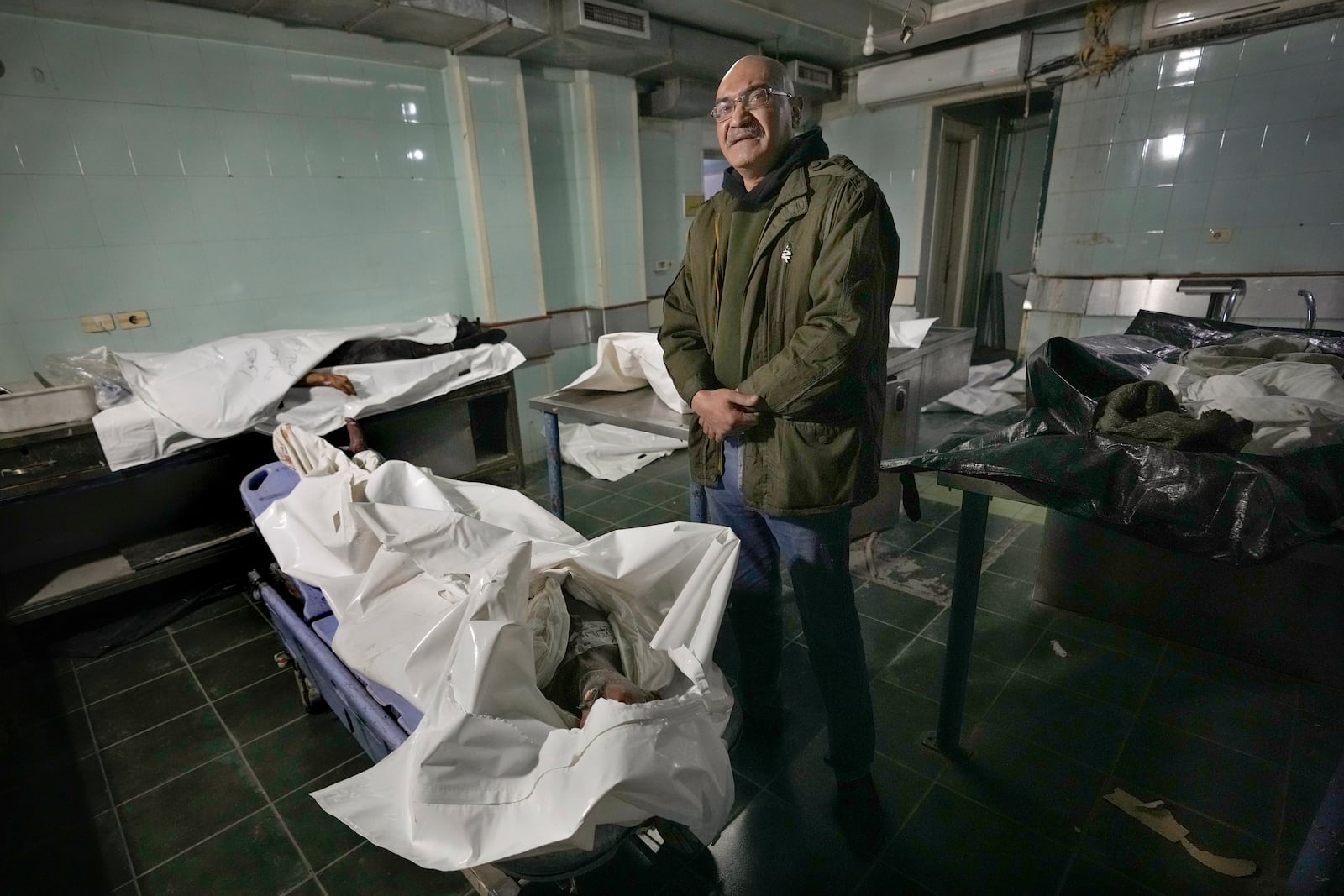 EDS NOTE: GRAPHIC CONTENT - Imad Habbal stands next to the body of his brother, Diaa Habbal, at the morgue of Al-Mojtahed Hospital in Damascus, Syria, on Wednesday, Dec. 11, 2024. Diaa was arrested by the Syrian military police six months ago after returning to Damascus from Saudi Arabia, where he had been living since 2003. He came back in mid-2024 to visit his family and was arrested on charges of evading military service. (AP Photo/Hussein Malla)