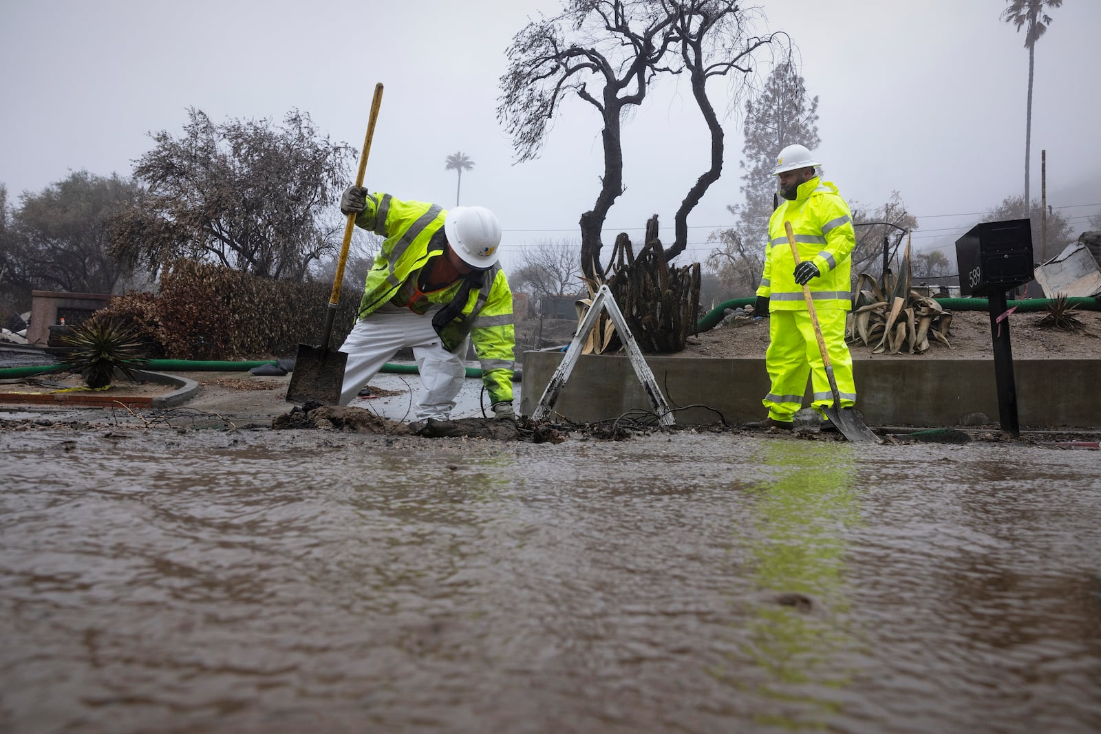 Crews work in the rain in the Eaton Fire zone during a storm Thursday, Feb. 13, 2025, in Altadena, Calif. (AP Photo/Etienne Laurent)