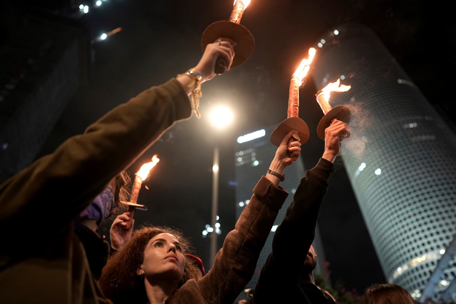 Demonstrators hold torches as they gather during a protest calling for the release of all hostages held captive by Hamas in the Gaza Strip, in Tel Aviv, Israel on Saturday, Jan. 18, 2025. (AP Photo/Oded Balilty)