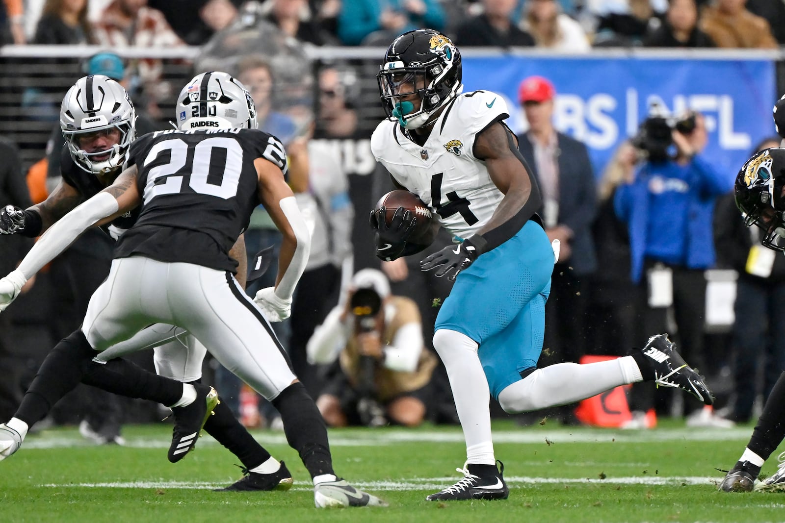 Jacksonville Jaguars running back Tank Bigsby (4) runs for a first down against the Las Vegas Raiders defense, including Raiders safety Isaiah Pola-Mao (20), during the first half of an NFL football game Sunday, Dec. 22, 2024, in Las Vegas. (AP Photo/David Becker)