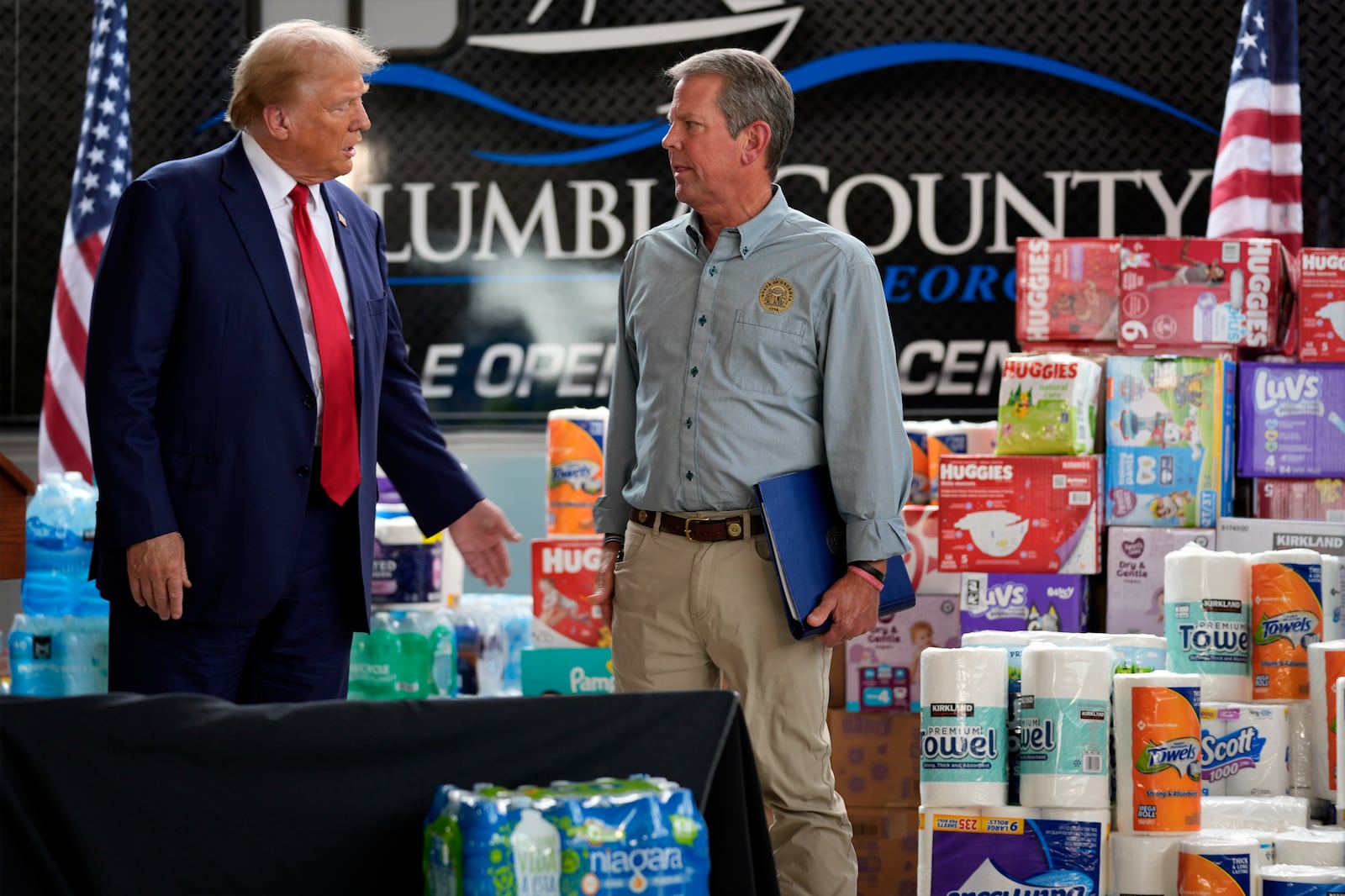 Republican presidential nominee former President Donald Trump talks with Georgia Gov. Brian Kemp after speaking at a temporary relief shelter as he visits areas impacted by Hurricane Helene, Friday, Oct. 4, 2024, in Evans, Ga. (AP Photo/Evan Vucci)