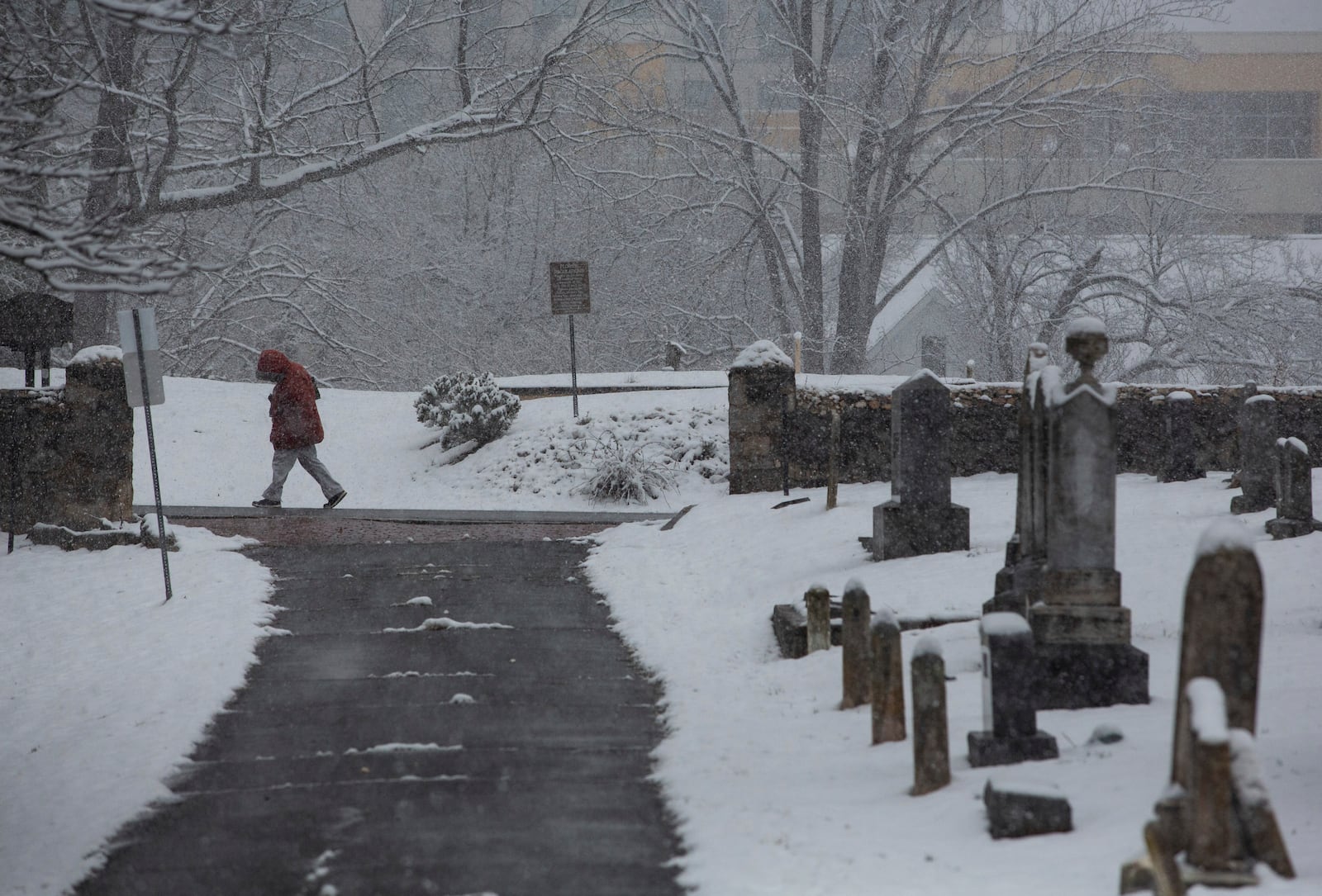 A person walks by Oakwood Cemetery as a winter snowstorm hits Charlottesville, Va., Tuesday, Feb. 11, 2025. (Cal Cary/The Daily Progress via AP)