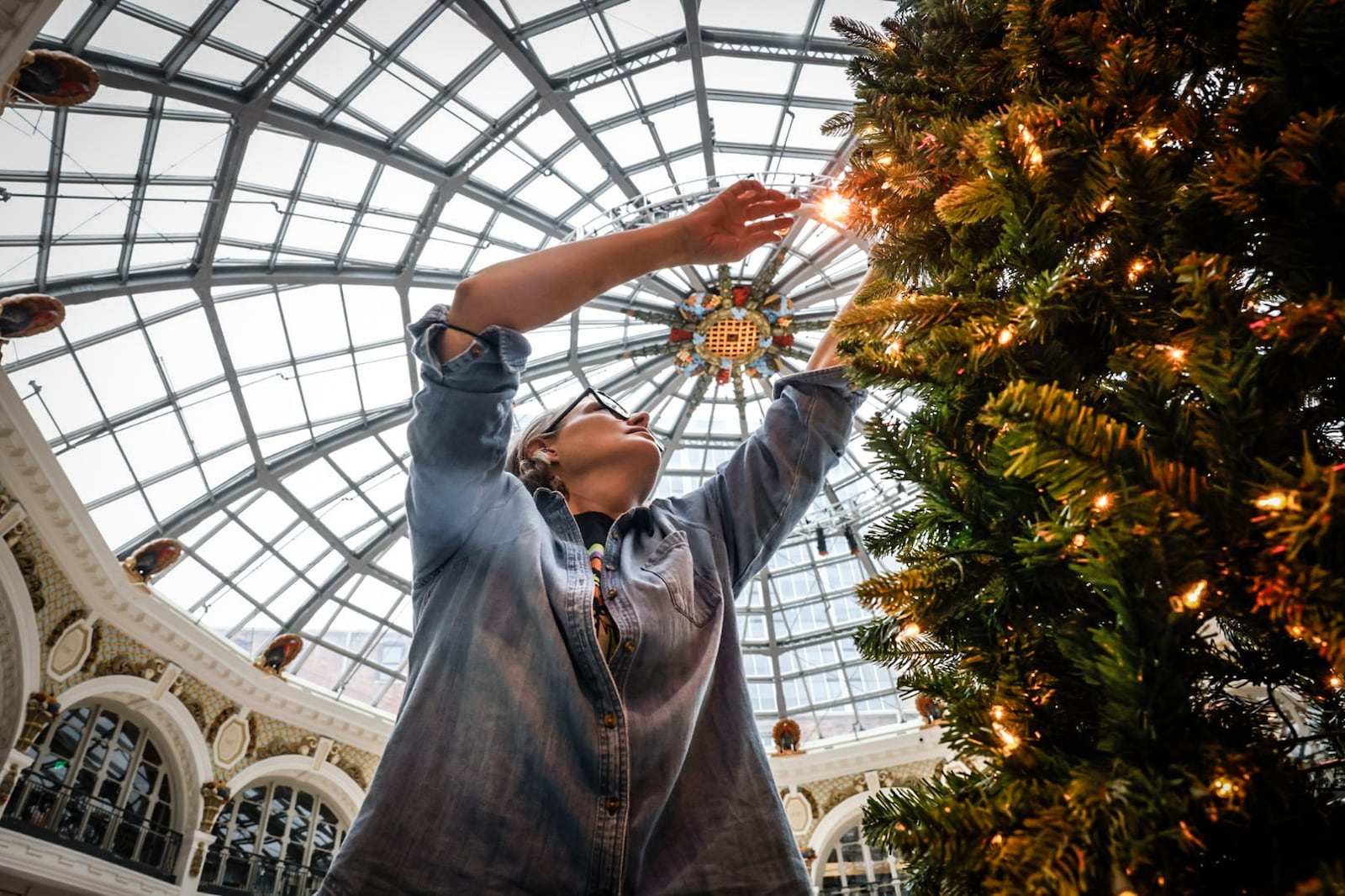 Friends of the Dayton Arcade volunteer Anna Hunsberger fluffs Christmas trees at the Dayton Arcade Monday December 9, 2024. Hunsberger and other volunteers put together dozens of trees in the rotunda for Holly Days 2024. JIM NOELKER/STAFF