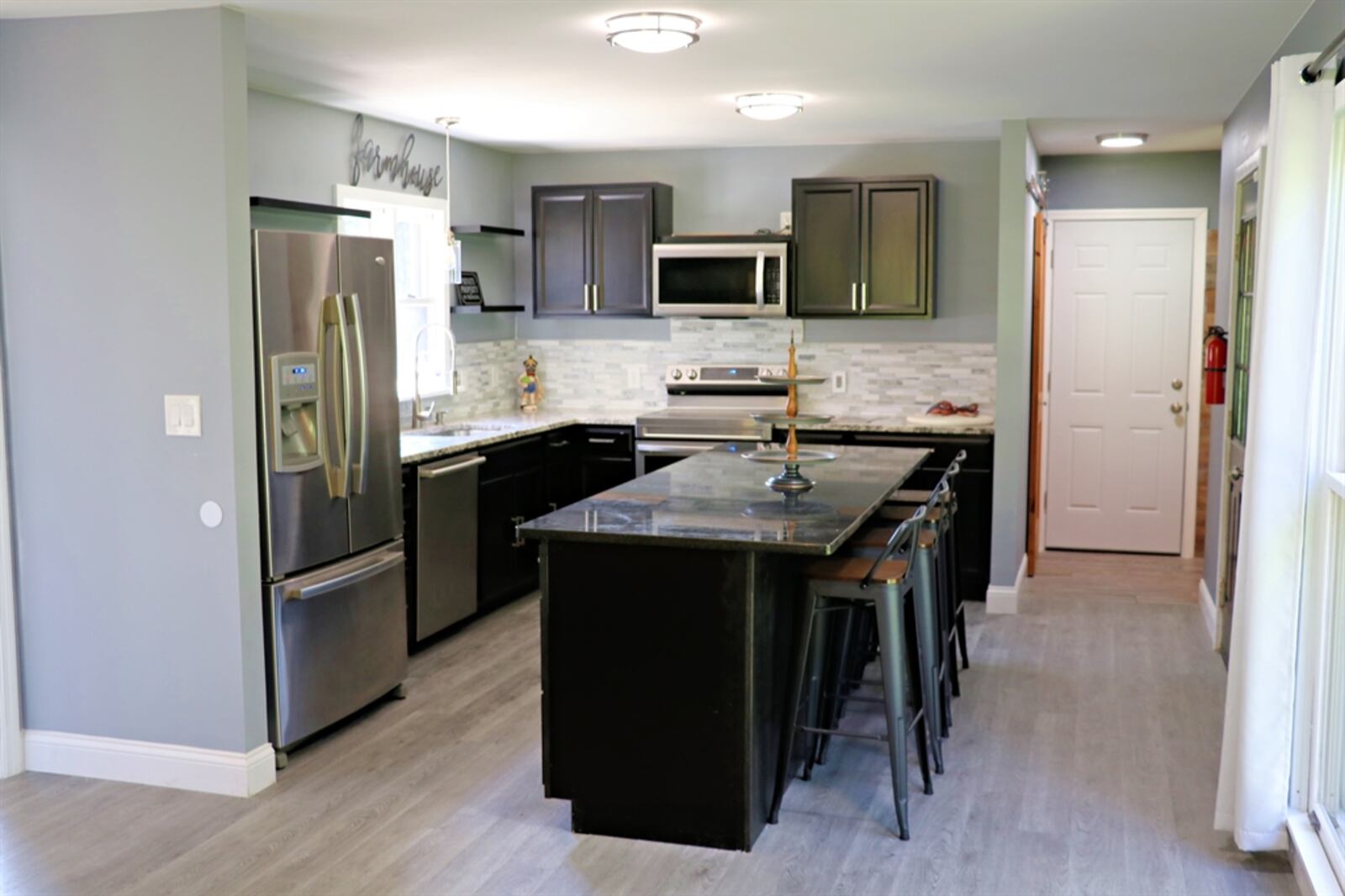 The kitchen has a long island with a dark granite counter that is extended to allow for breakfast bar seating.