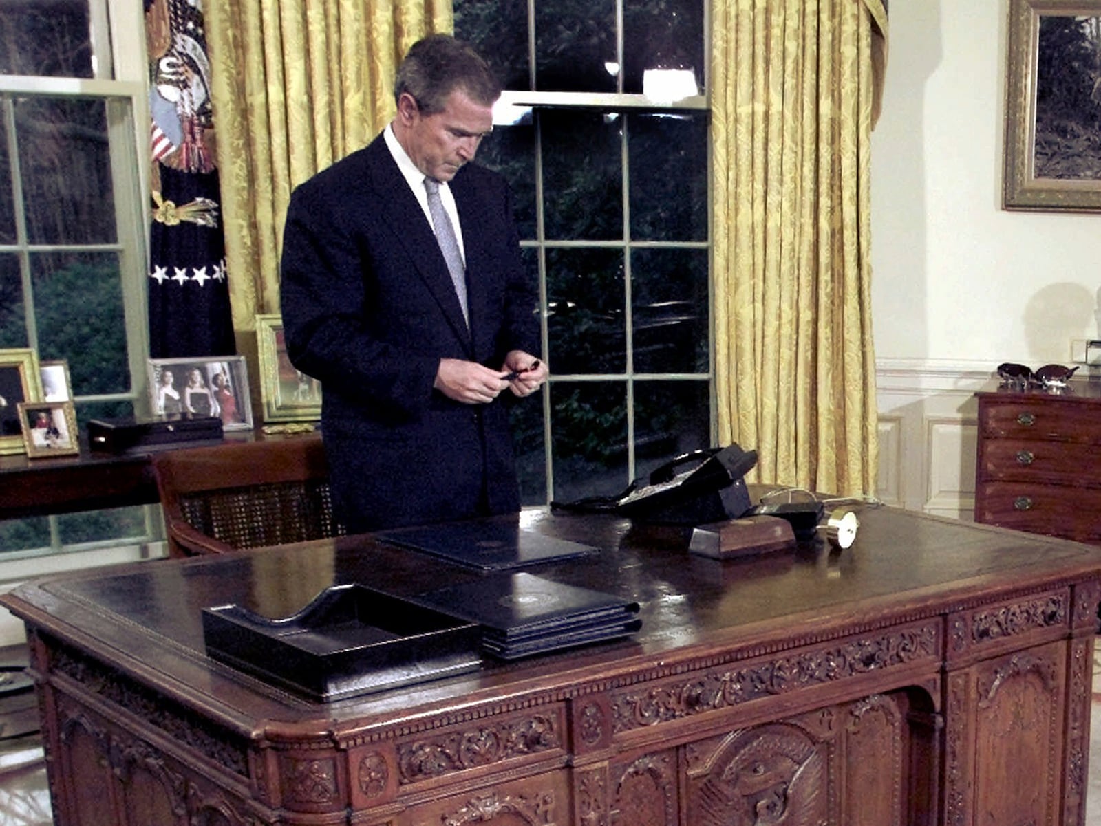 FILE - President George W. Bush pauses at his desk after he signed a Joint Resolution commemorating Ronald Reagan's 90th birthday in the Oval Office of the White House, Feb. 15, 2001. (AP Photo/Ron Edmonds, File)