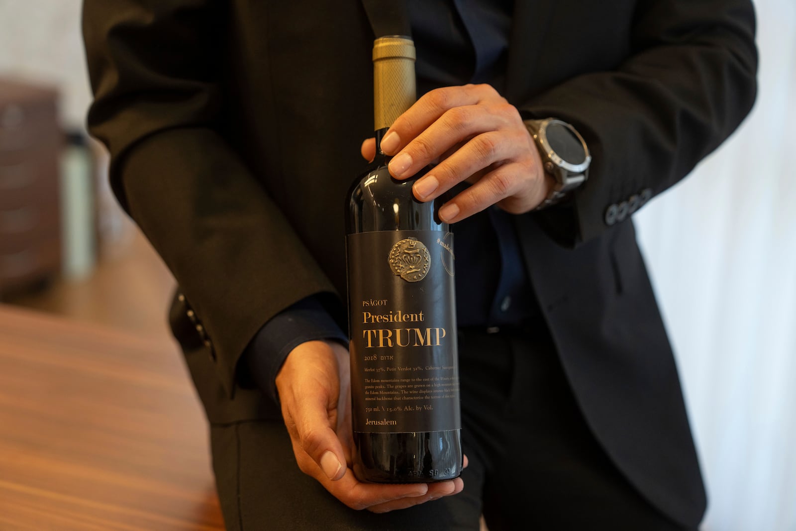 Israel Ganz, chairman of the Yesha settlers council and head of the Mateh Binyamin Regional Council, poses for a portrait holding a bottle of wine bearing the name of U.S. President-elect Donald Trump in the Shaar Binyamin Industrial Park in the West Bank, Monday, Nov. 11, 2024. (AP Photo/Ohad Zwigenberg)