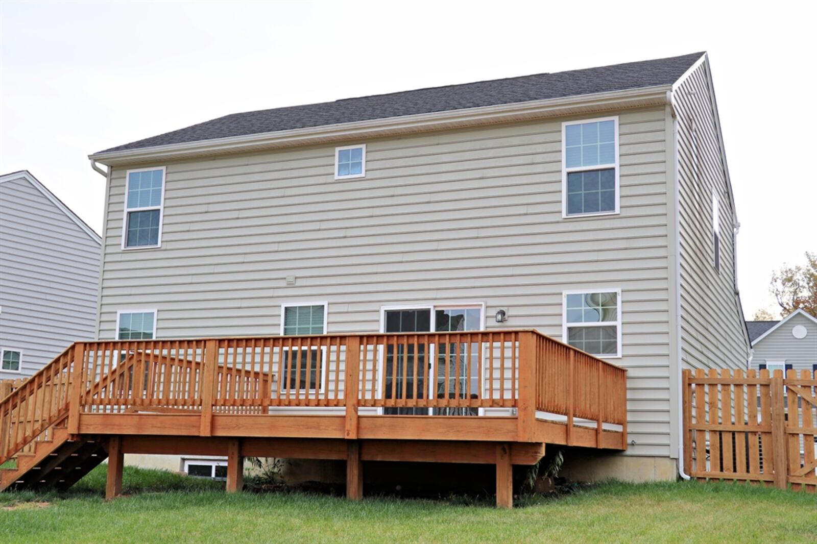 A wooden picket privacy fence surrounds the backyard, which includes a raised garden and a fire pit.