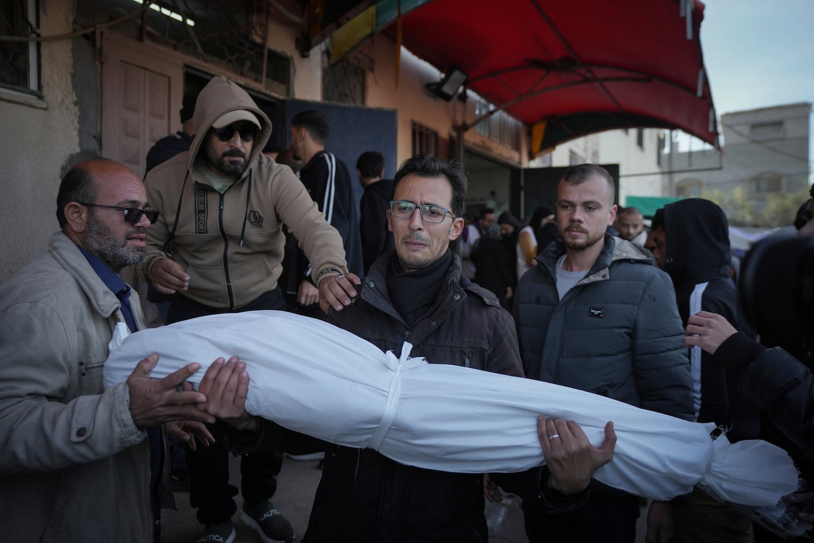 Waleed Shaqoura carries the body of his nephew, Mohammad Shaqoura, 7, who was killed in the Israeli bombardment of the Gaza Strip, during his funeral in Deir al-Balah, Wednesday, Jan. 15, 2025. (AP Photo/Abdel Kareem Hana)