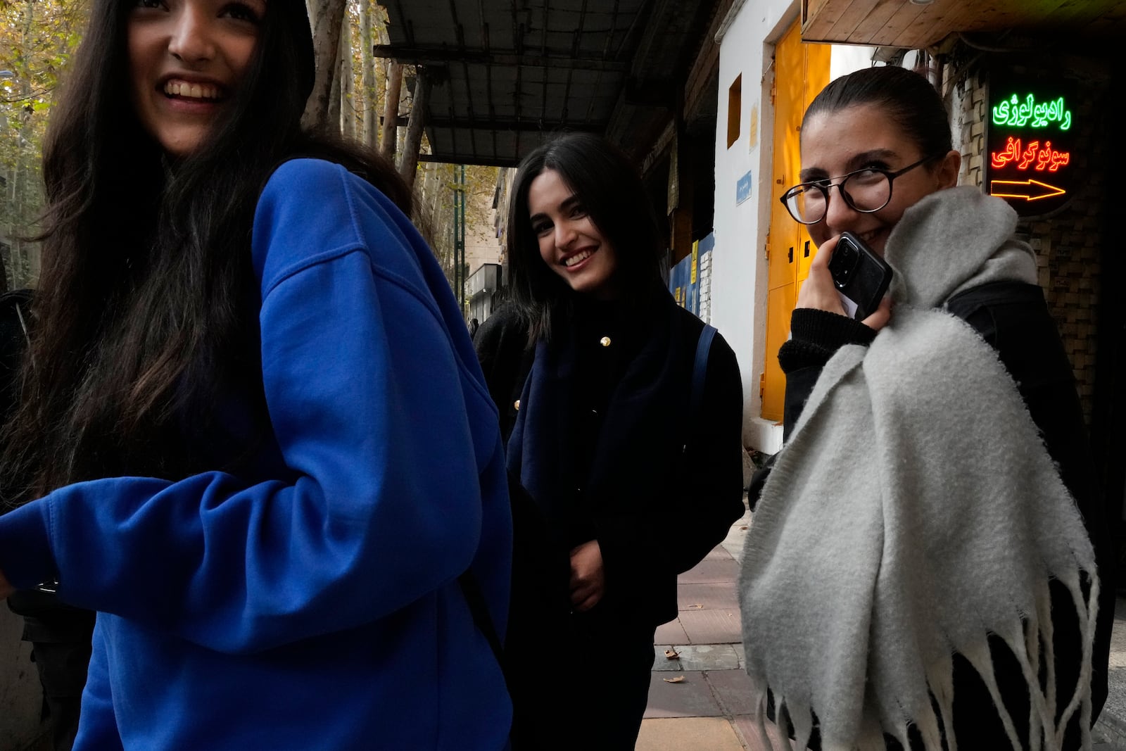 Iranian women, without wearing their mandatory Islamic headscarves, share a laugh while walking in northern Tehran, Iran, Friday, Nov. 15, 2024. (AP Photo/Vahid Salemi)