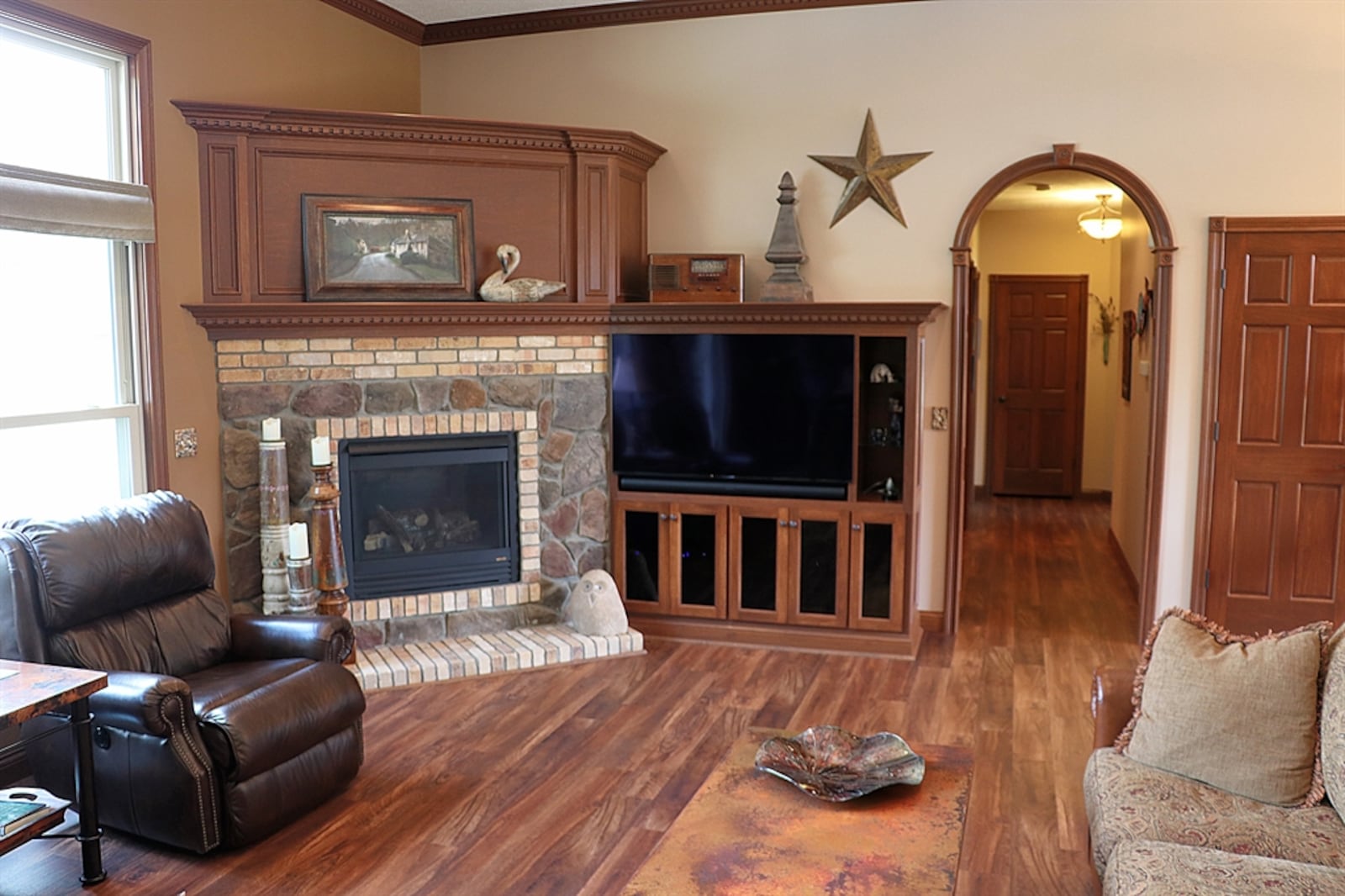 Tucked into a corner of the great room is a gas fireplace with a dentil wooden mantel. Bookcases and display nooks highlight the media area.