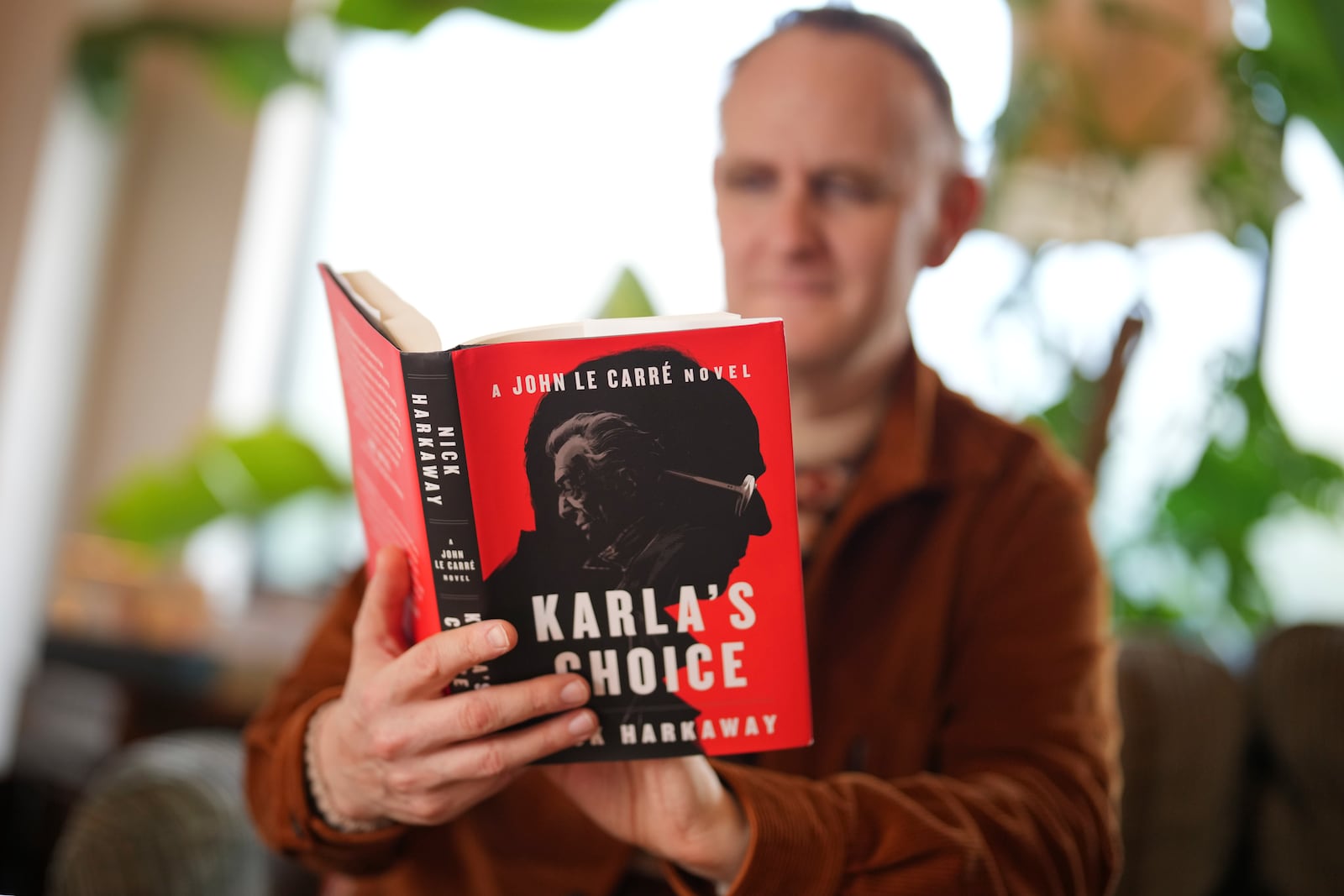 British author Nick Harkaway, son of John le Carre, holds a copy of his book, during an interview with The Associated Press, at his home, in London, Thursday, Oct. 24, 2024. (AP Photo/Kin Cheung)