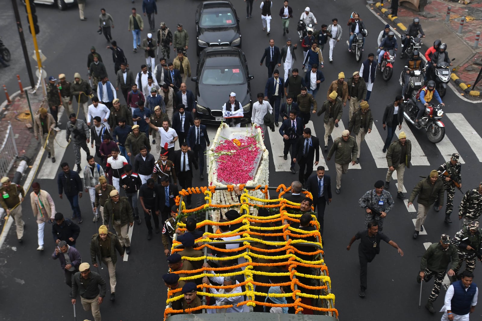 Security officials and others walk with the hearse carrying the body of former Indian Prime Minister Manmohan Singh towards the cremation site in New Delhi, India, Saturday, Dec. 28, 2024. (AP Photo)