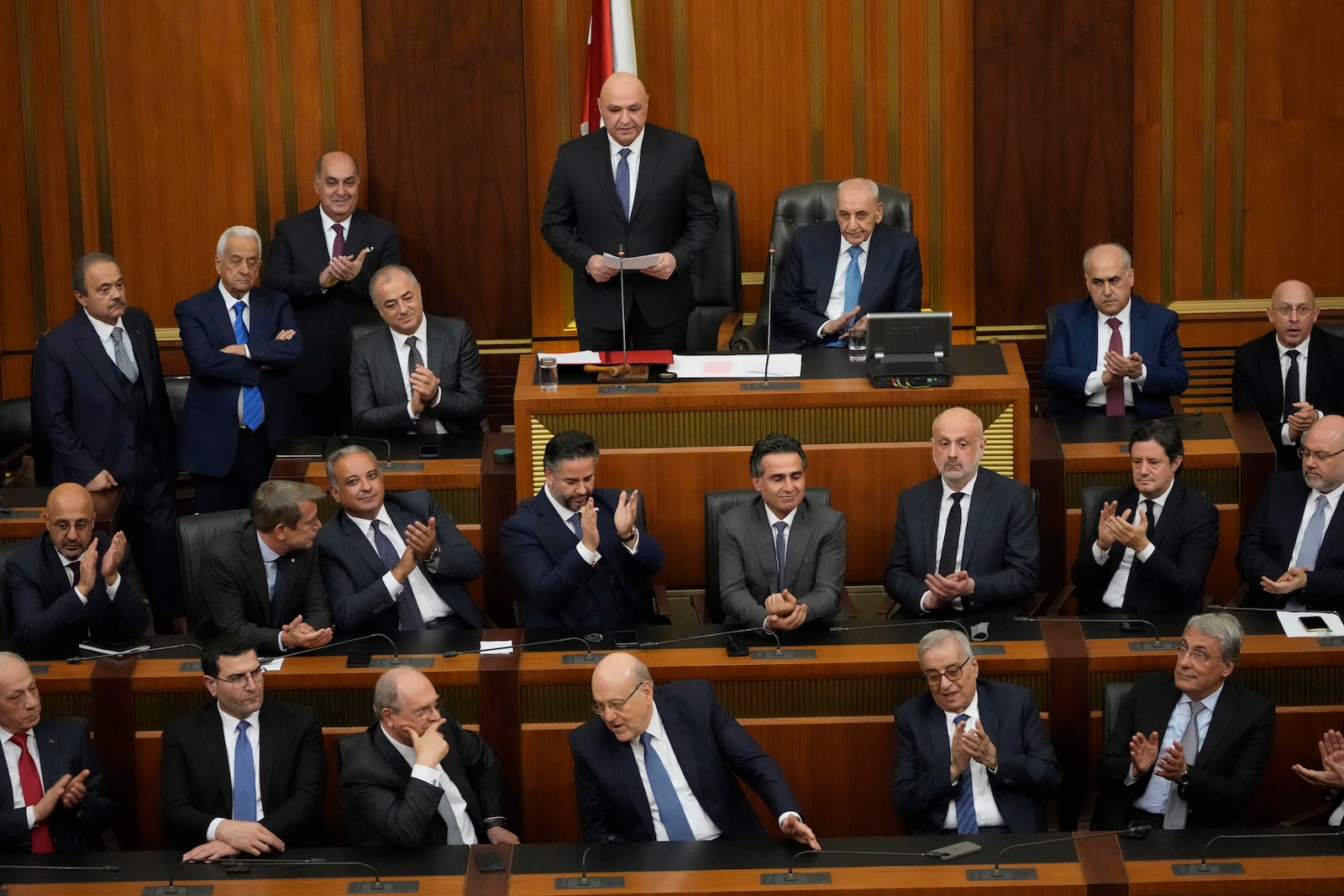 Lebanese cabinet ministers applaud the newly-elected Lebanese President Joseph Aoun, standing at background center, during addresses his first speech at the Lebanese Parliament after being sworn in as a new president, in Beirut, Lebanon, Thursday, Jan. 9, 2025.(AP Photo/Hussein Malla)