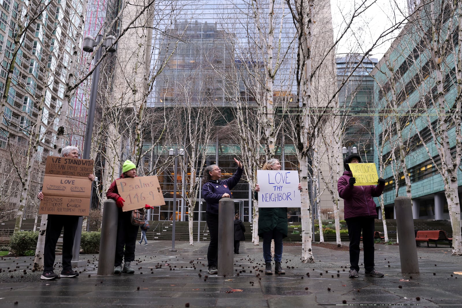 People hold signs as they gather outside the U.S. District Court after a federal judge blocked President Donald Trump's effort to halt the nation's refugee admissions system Tuesday, Feb. 25, 2025, in Seattle. (AP Photo/Ryan Sun)