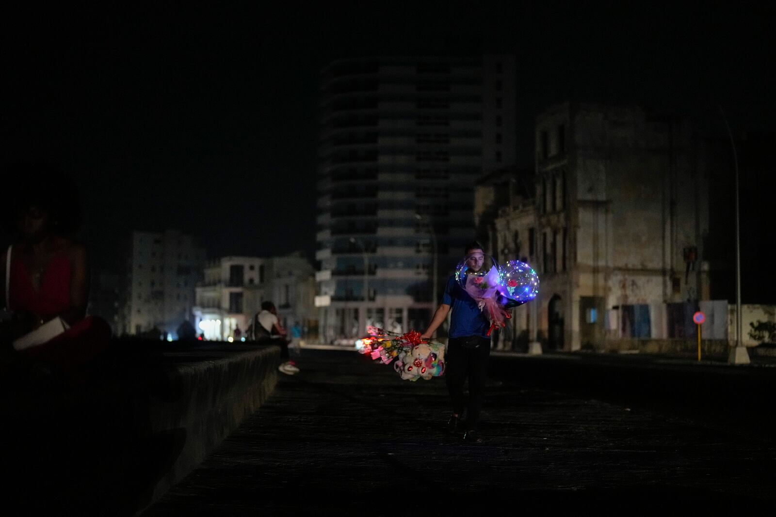 A street vendor walks along the Malecon looking for customers during a general blackout in Havana, Saturday, March 15, 2025. (AP Photo/Ramon Espinosa)