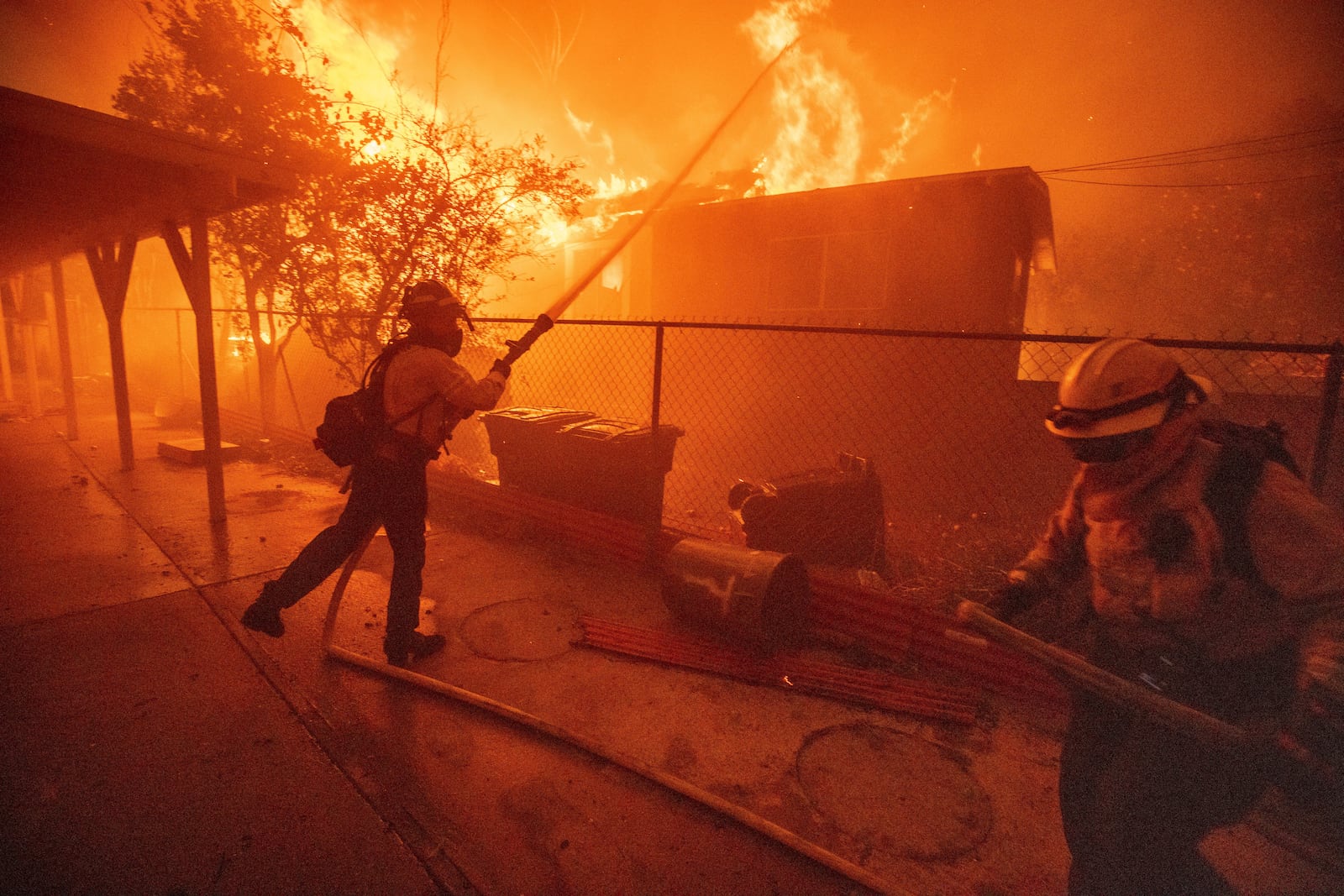 Firefighters protect a structure as the Eaton Fire advances Wednesday, Jan. 8, 2025 in Altadena, Calif. (AP Photo/Ethan Swope)