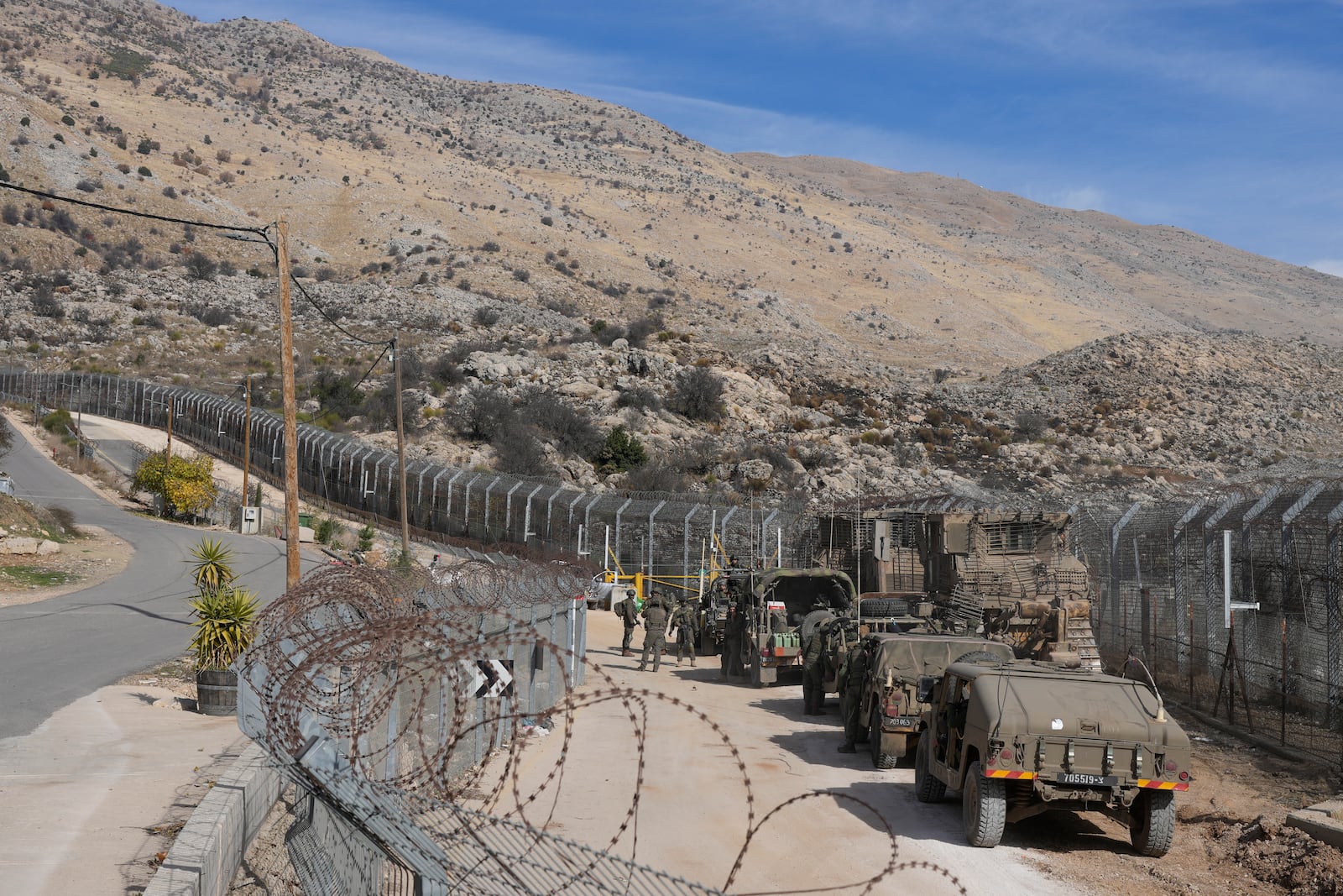 Israeli soldiers stand next to armoured vehicles before crossing the security fence, moving towards the so-called Alpha Line that separates the Israeli-controlled Golan Heights from Syria, in the town of Majdal Shams, Thursday, Dec. 12, 2024. (AP Photo/Matias Delacroix)