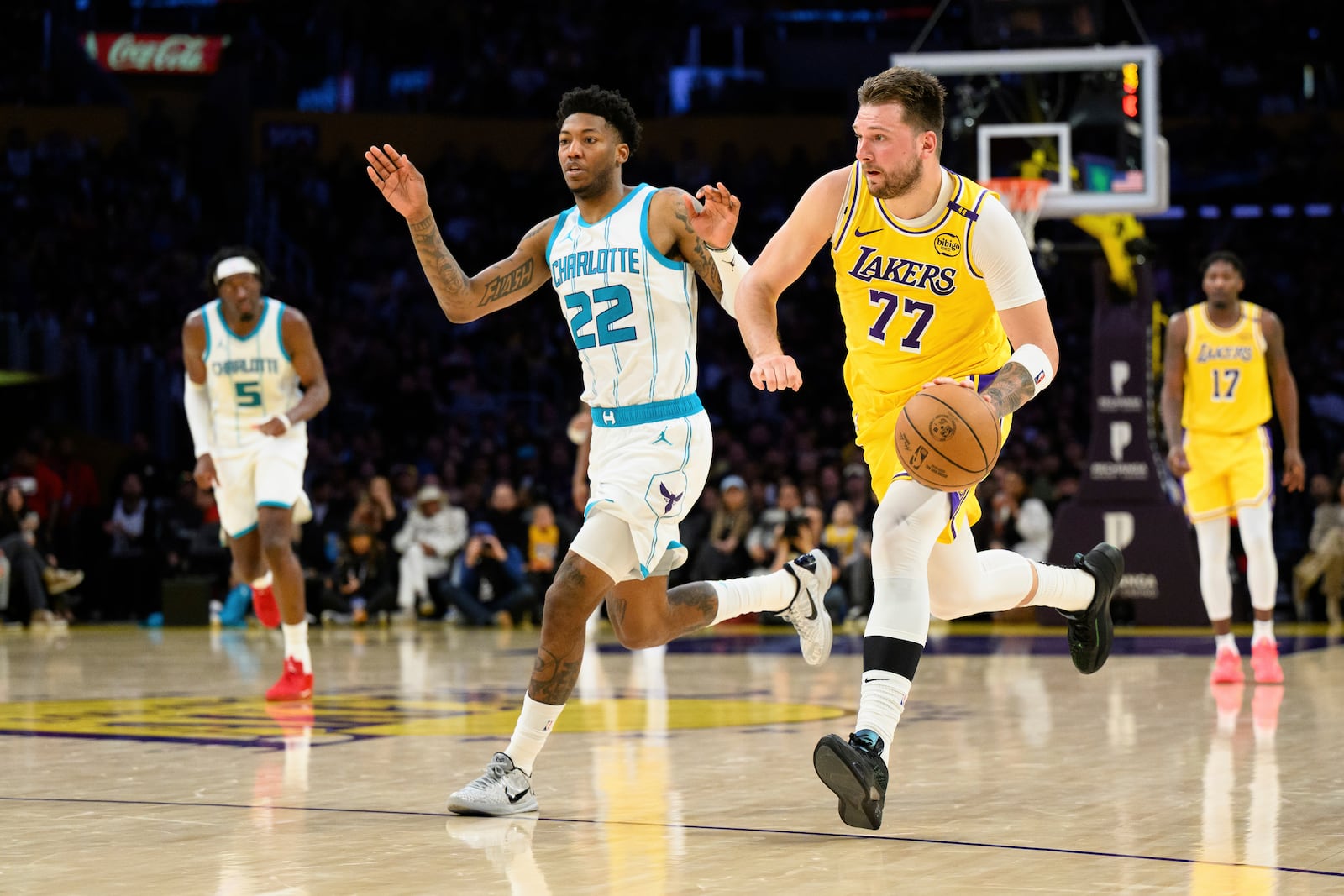 Los Angeles Lakers guard Luka Doncic (77) drives the ball while pursued by Charlotte Hornets guard Elfrid Payton (22) during the second half of an NBA basketball game Wednesday, Feb. 19, 2025, in Los Angeles. (AP Photo/William Liang)