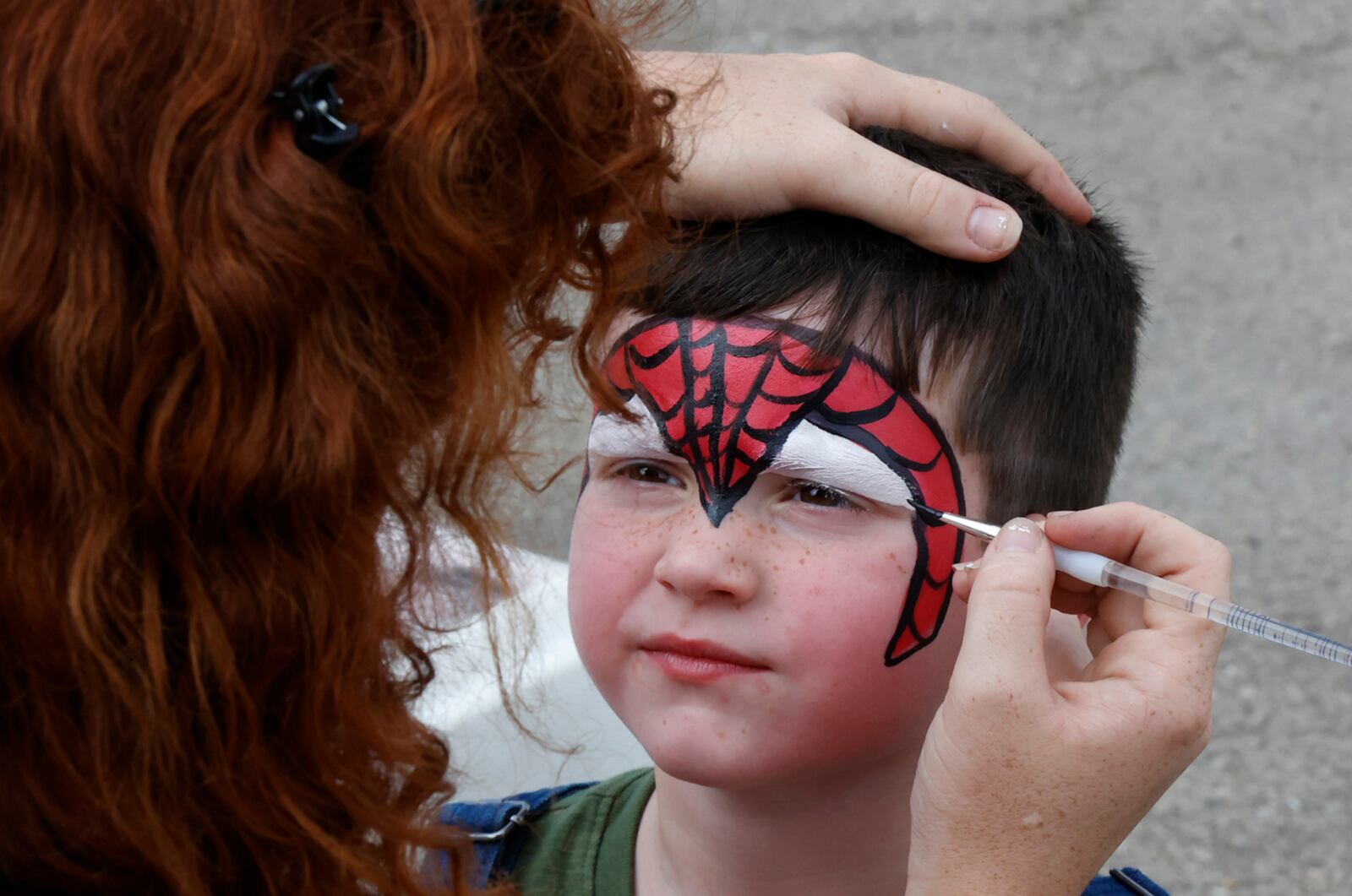 Isaac Peterson, 4, gets his face painted by a group from Cincinnati Circus Friday, August 11, 2023 at the Springfield Jazz & Blues Festival. BILL LACKEY/STAFF