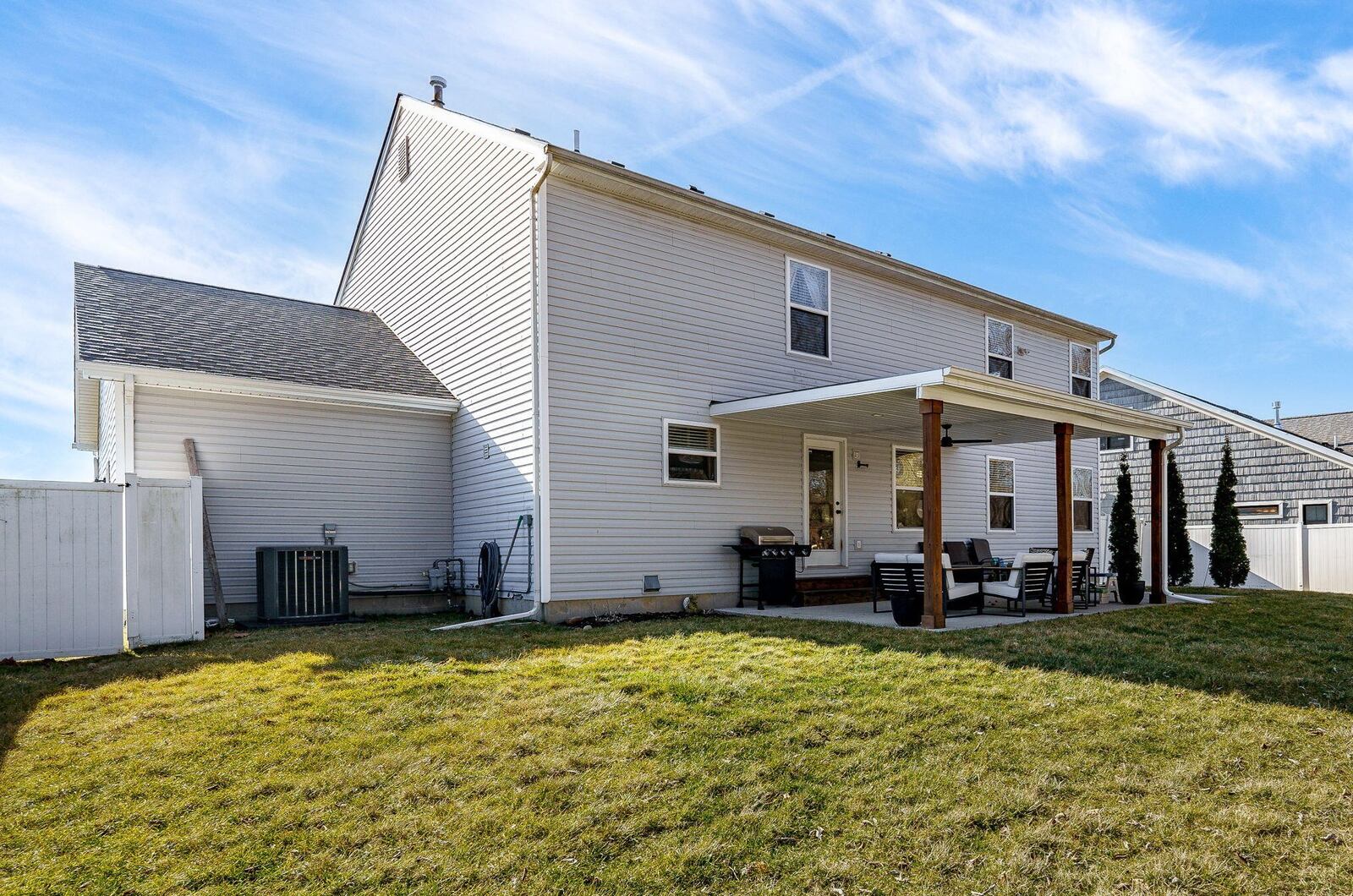 The back of the home features a covered concrete patio with a ceiling fan and lighting.