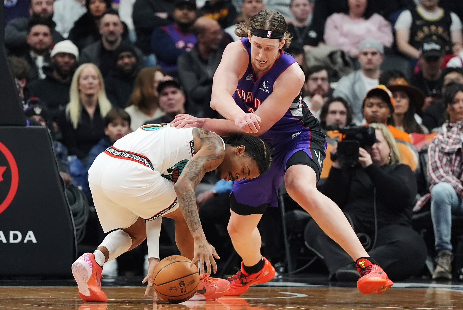 Memphis Grizzlies' Ja Morant (left) and Toronto Raptors' Kelly Olynyk (41) battle for the ball during first half NBA basketball action in Toronto on Wednesday, Feb. 5, 2025. (Frank Gunn/The Canadian Press via AP)