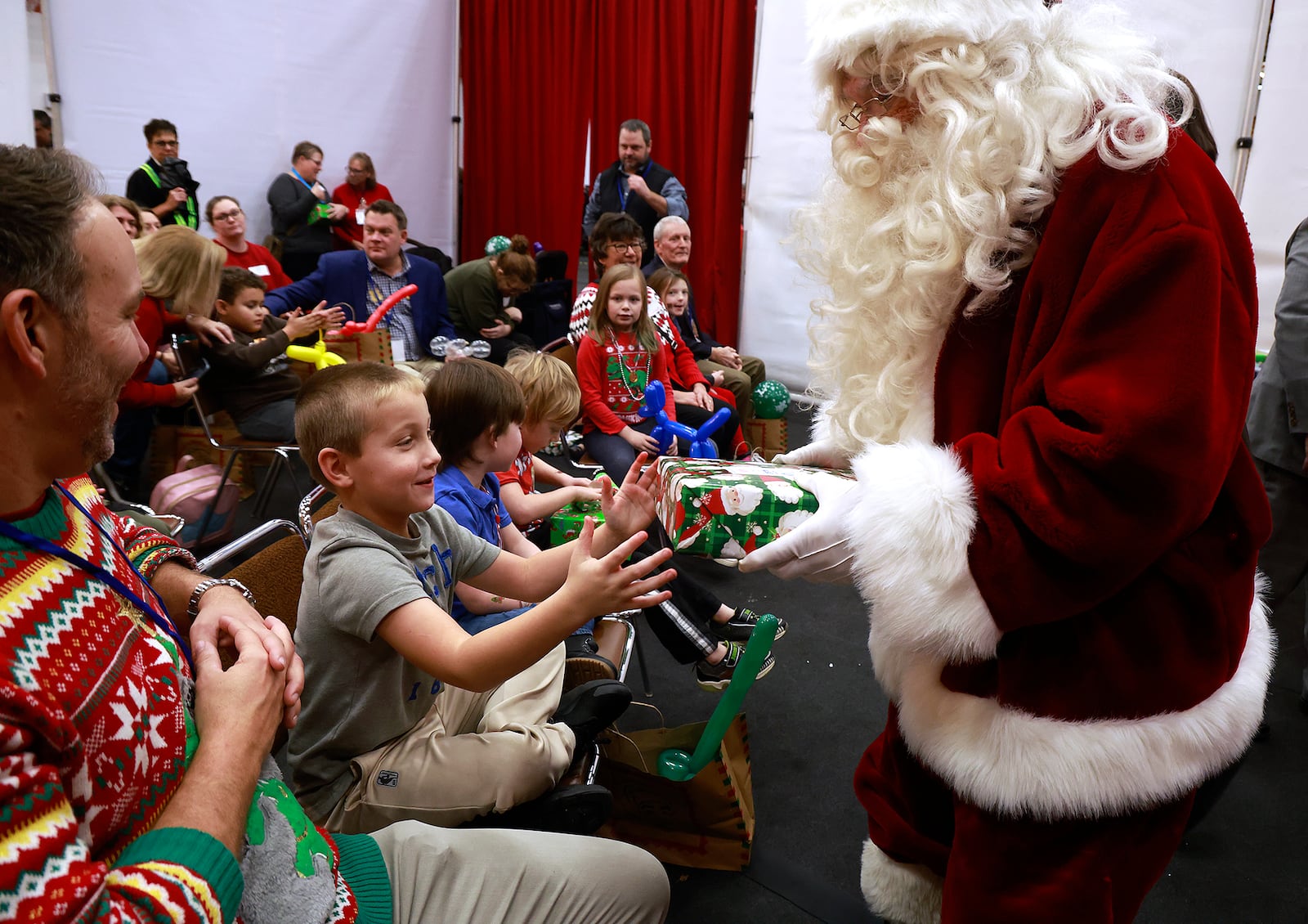 Bentlee Arrasmith, a third grader at Northwestern Elementary, receives a gift from Santa at the Springfield Rotary Club's 102nd Children's with Disabilities Christmas Party at Wittenberg University Monday, Dec. 9, 2024. BILL LACKEY/STAFF