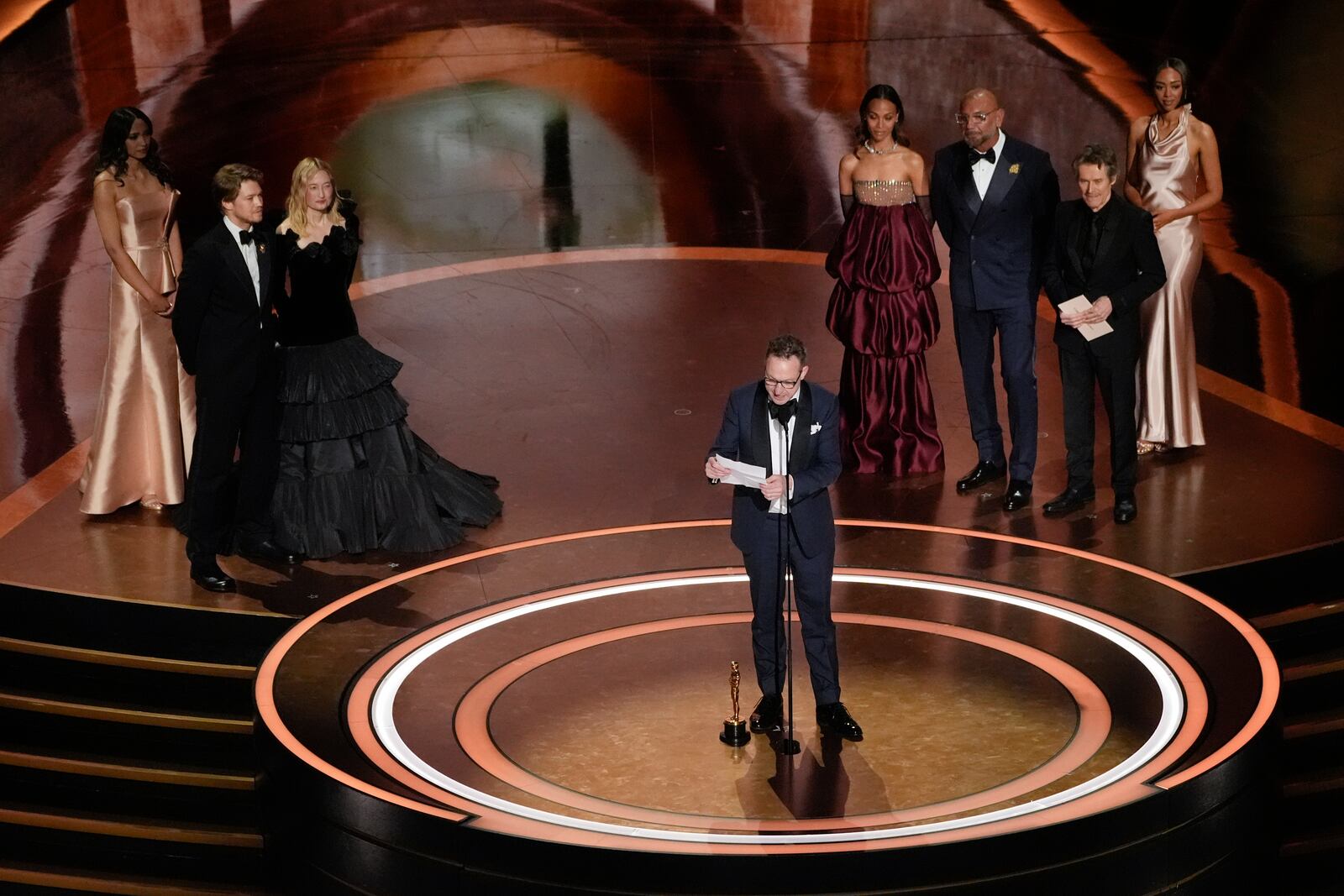 Walter Salles, center, accepts the award for "I'm Still Here" from Brazil, for best international feature film during the Oscars on Sunday, March 2, 2025, at the Dolby Theatre in Los Angeles. Joe Alwyn, from left, Alba Rohrwacher, Zoe Saldana, Dave Bautista, and Willem Dafoe look on from rear of the stage.(AP Photo/Chris Pizzello)