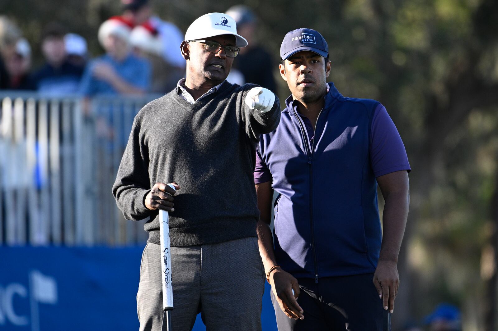 Vijay Singh, left, and his son Qass Singh line up their putt on the 18th green during the first round of the PNC Championship golf tournament, Saturday, Dec. 21, 2024, in Orlando, Fla. (AP Photo/Phelan M. Ebenhack)