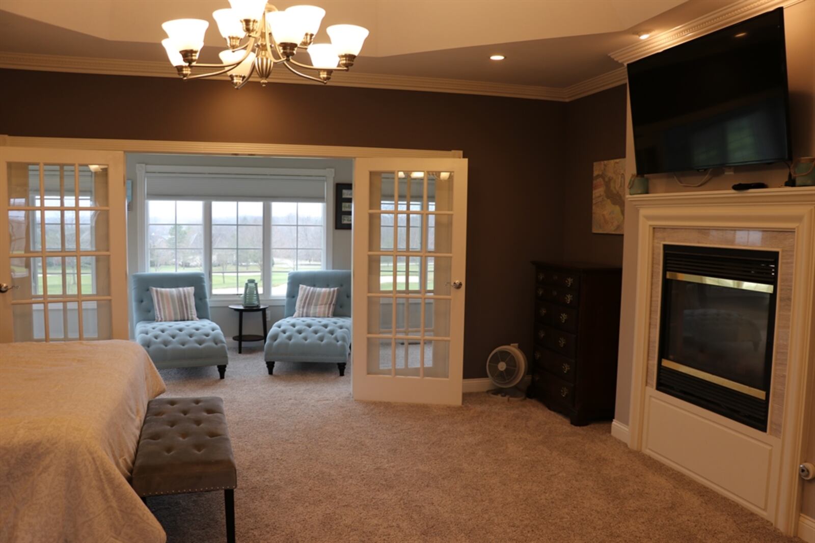 A deep tray ceiling gives the master bedroom suite an open feel and oversized French doors open out to a sunroom that looks out over the fairway. 