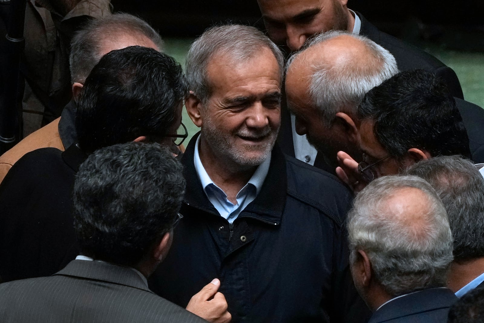 Iranian President Masoud Pezeshkian, center, listens to a lawmaker after speaking on his next year's budget bill in an open session of parliament, in Tehran, Iran, Tuesday, Oct. 29, 2024. (AP Photo/Vahid Salemi)