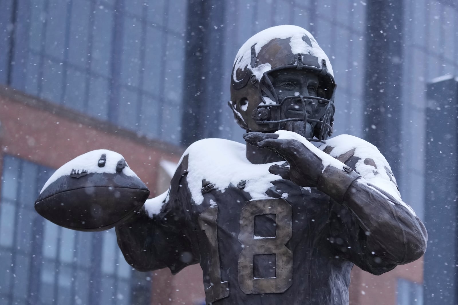 A statue of Peyton Manning by Ryan Feeney is covered with snow outside Lucas Oil Stadium after an NFL football game between the Indianapolis Colts and the Jacksonville Jaguars, Sunday, Jan. 5, 2025, in Indianapolis. The Colts won 26-23 in overtime. (AP Photo/Michael Conroy)