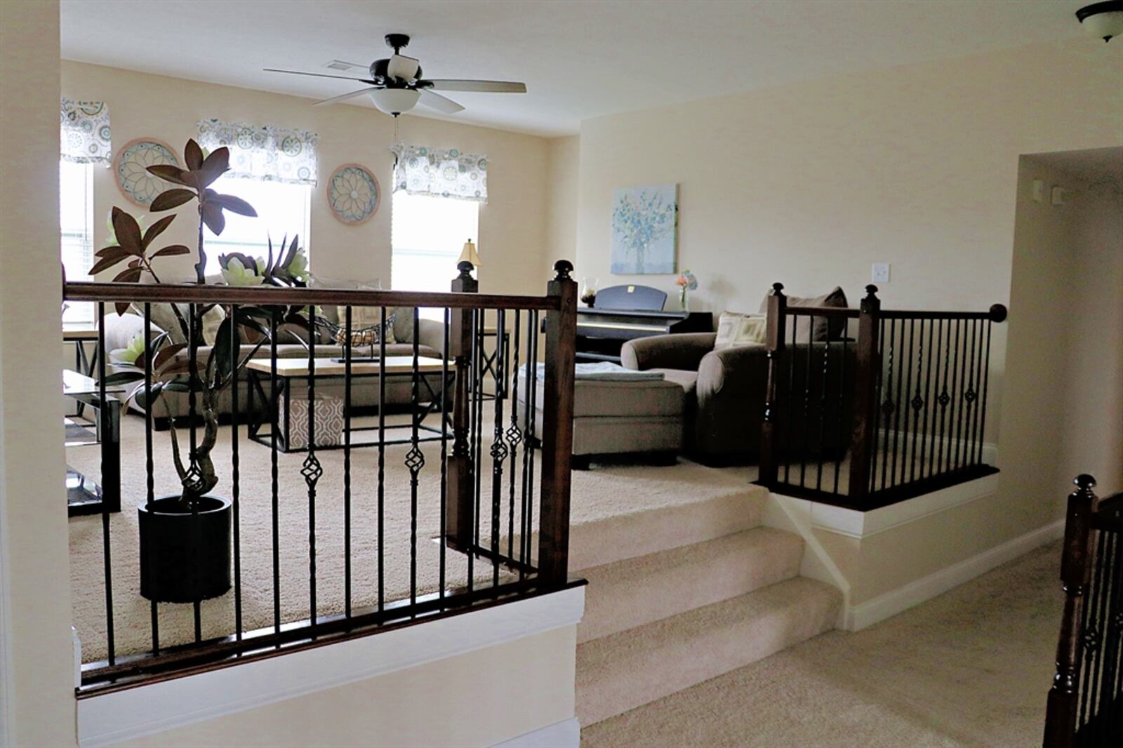 The stairwell opens into the hallway with wrought-iron spindle accents that also wrap around the elevated loft family room.