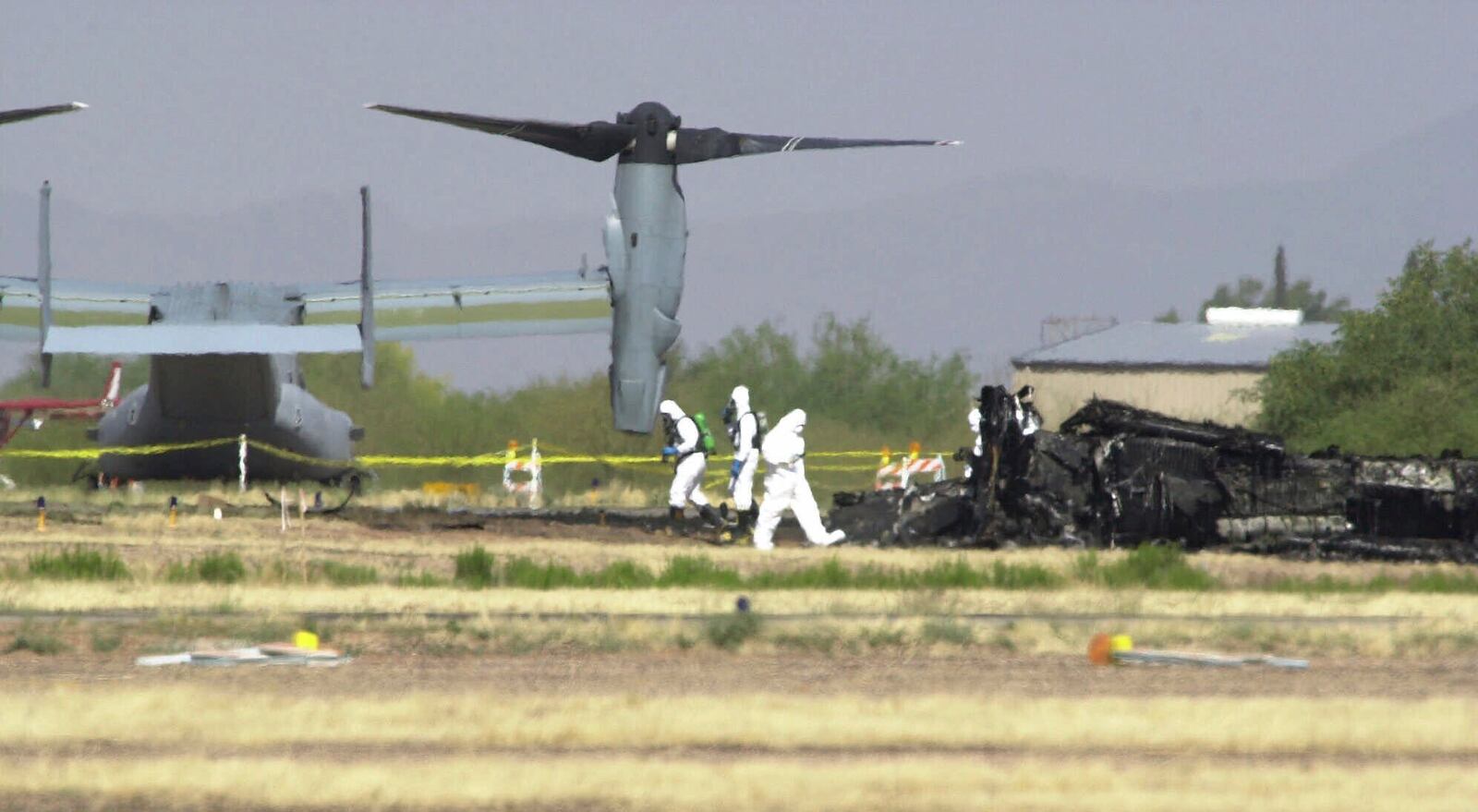 FILE - White suited workers investigate the crash scene of a Marine Corps MV-22 Osprey at the Avra Valley Airport, north of Tucson, Ariz., April 9, 2000. A Marine Corps aircraft attempting to land during a nighttime training mission crashed and burst into flames, killing all 19 aboard and adding to a checkered history for a new breed of hybrid plane that can take off and land like a helicopter. (AP Photo/Jon Hayt, File)