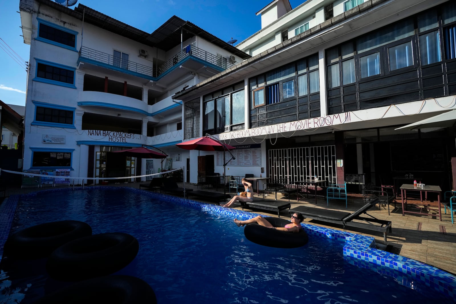 Foreign tourists relax at a swimming pool at Nana Backpack hostel in Vang Vieng, Laos, Tuesday, Nov. 19, 2024. (AP Photo/Anupam Nath)