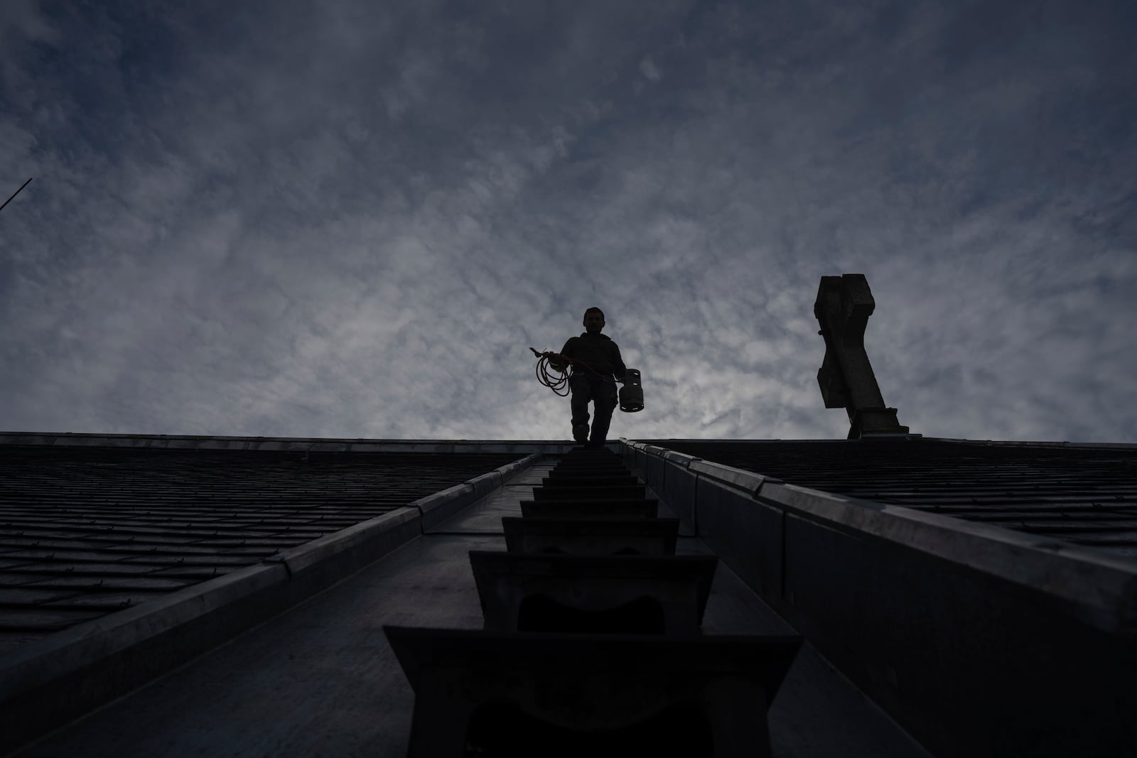 A roofer works on a church in Paris, Tuesday, Oct. 15, 2024. (AP Photo/Louise Delmotte)