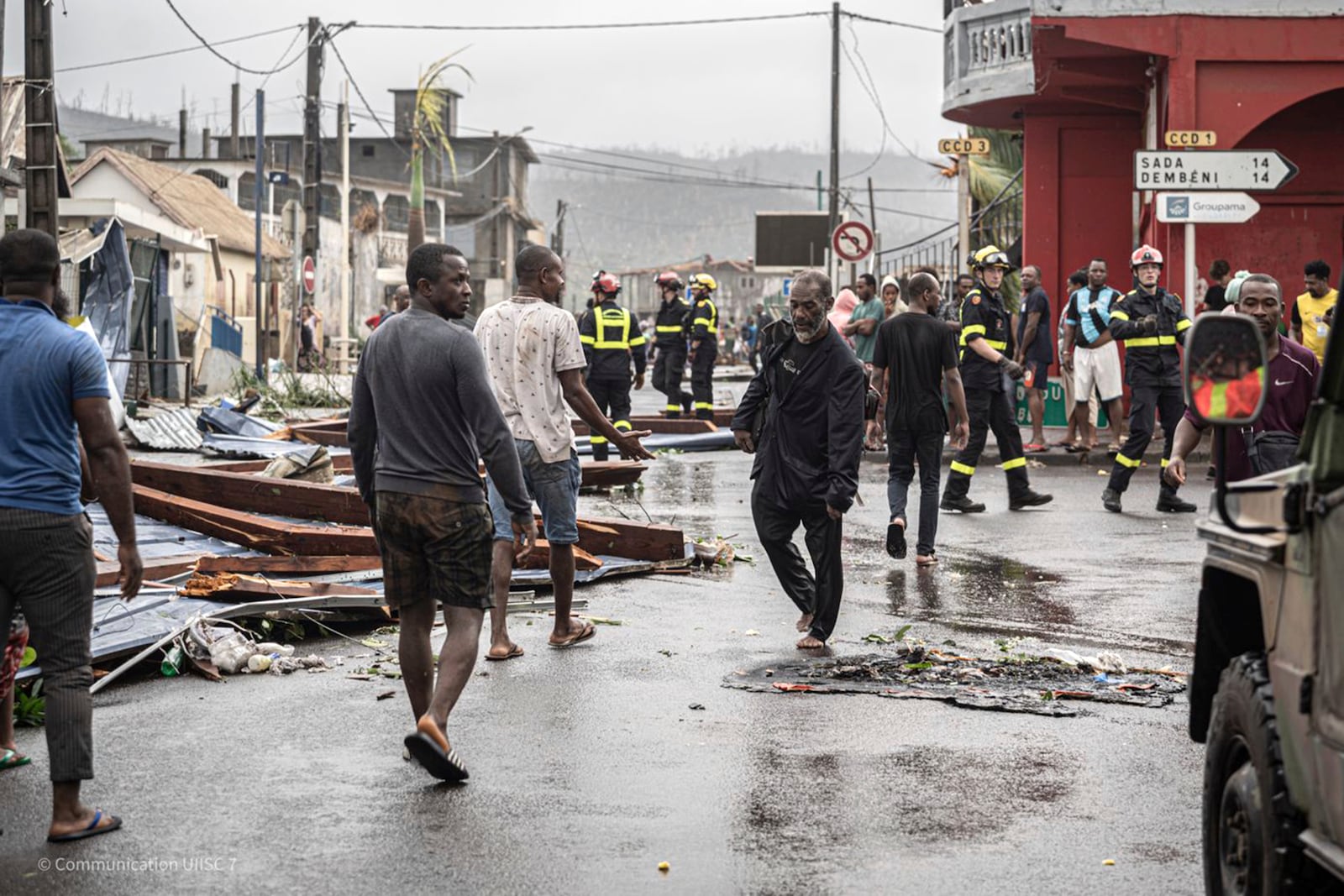 This photo provided on Monday Dec. 16, 2024 by the Civil Security shows residents and rescue workers walking in a damaged street in French territory of Mayotte in the Indian Ocean, after the island was battered by its worst cyclone in nearly a century. (UIISC7/Securite Civile via AP)