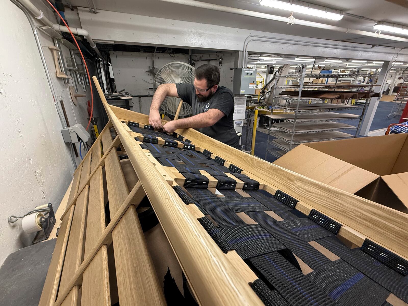 Built by Newport furniture company employee Eric Benware puts webbing on a sofa after the business's owner, Dave Laforce, who sources material from Canada, attended a roundtable event with U.S. Sen. Peter Welch of Vermont and Marie-Claude Bibeau, a Canadian member of parliament, to discuss the Trump administration's tariffs, Tuesday, March 18, 2025, in Newport, Vt. (AP Photo/Amanda Swinhart)