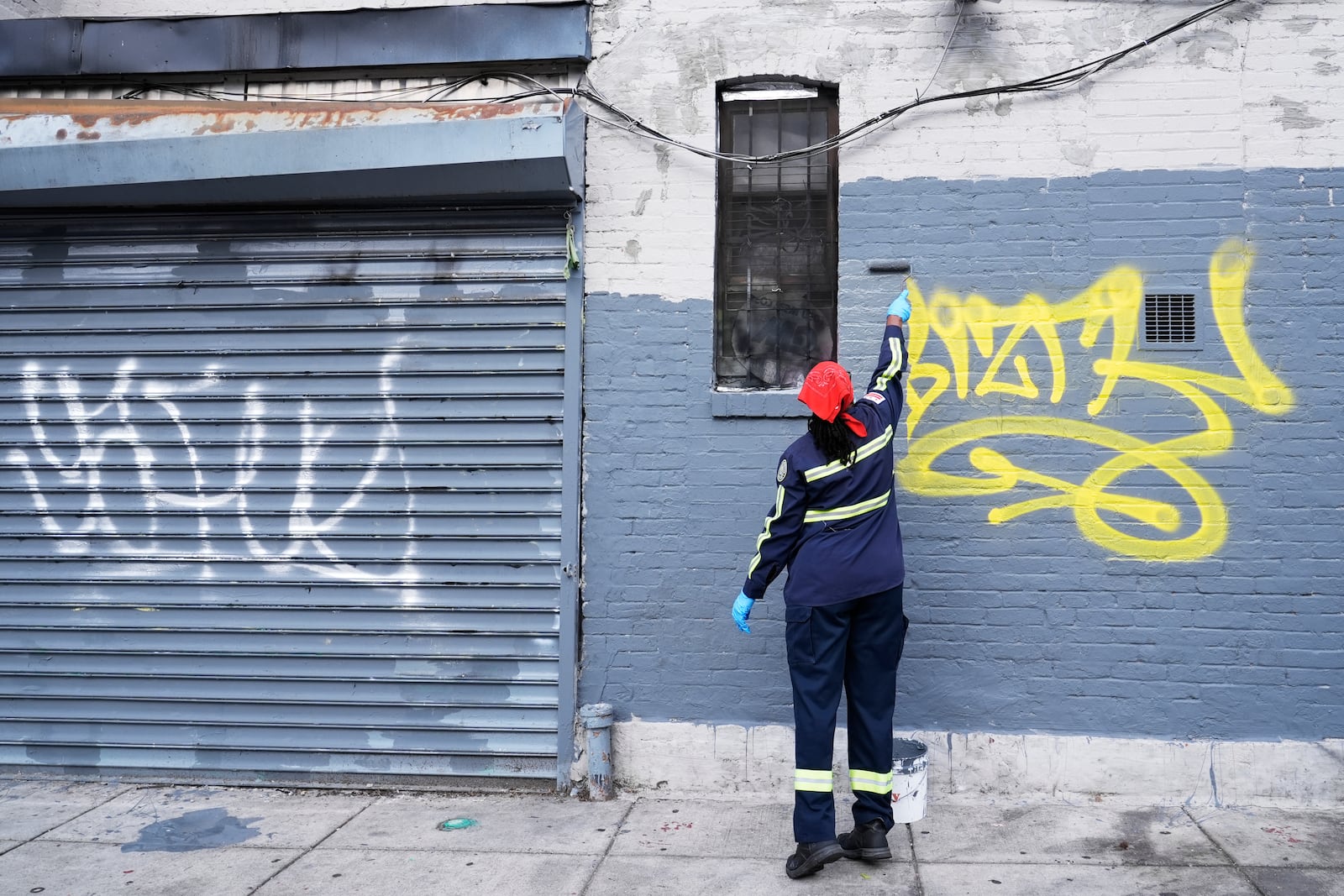 Queen Jones paints over graffiti on a building in Washington, Tuesday, Aug. 20, 2024. (AP Photo/Susan Walsh)