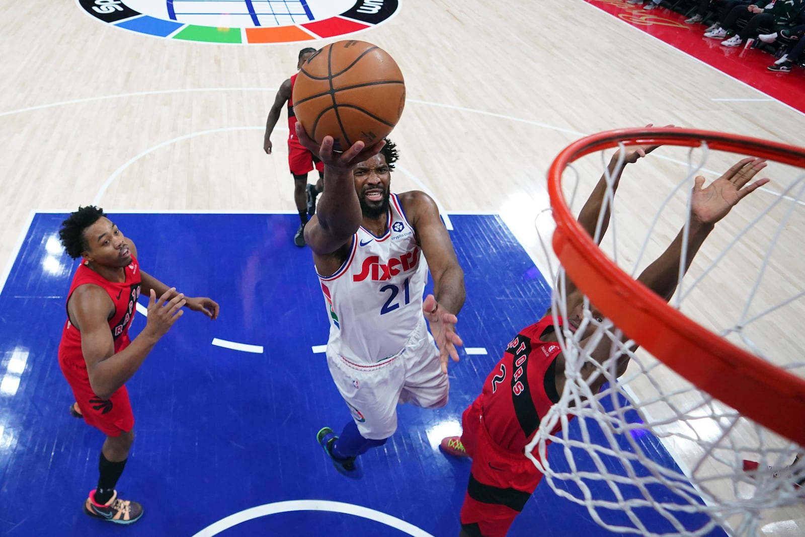 Philadelphia 76ers' Joel Embiid, center, goes up for a shot against Toronto Raptors' Jonathan Mogbo during the second half of an NBA basketball game, Tuesday, Feb. 11, 2025, in Philadelphia. (AP Photo/Matt Slocum)