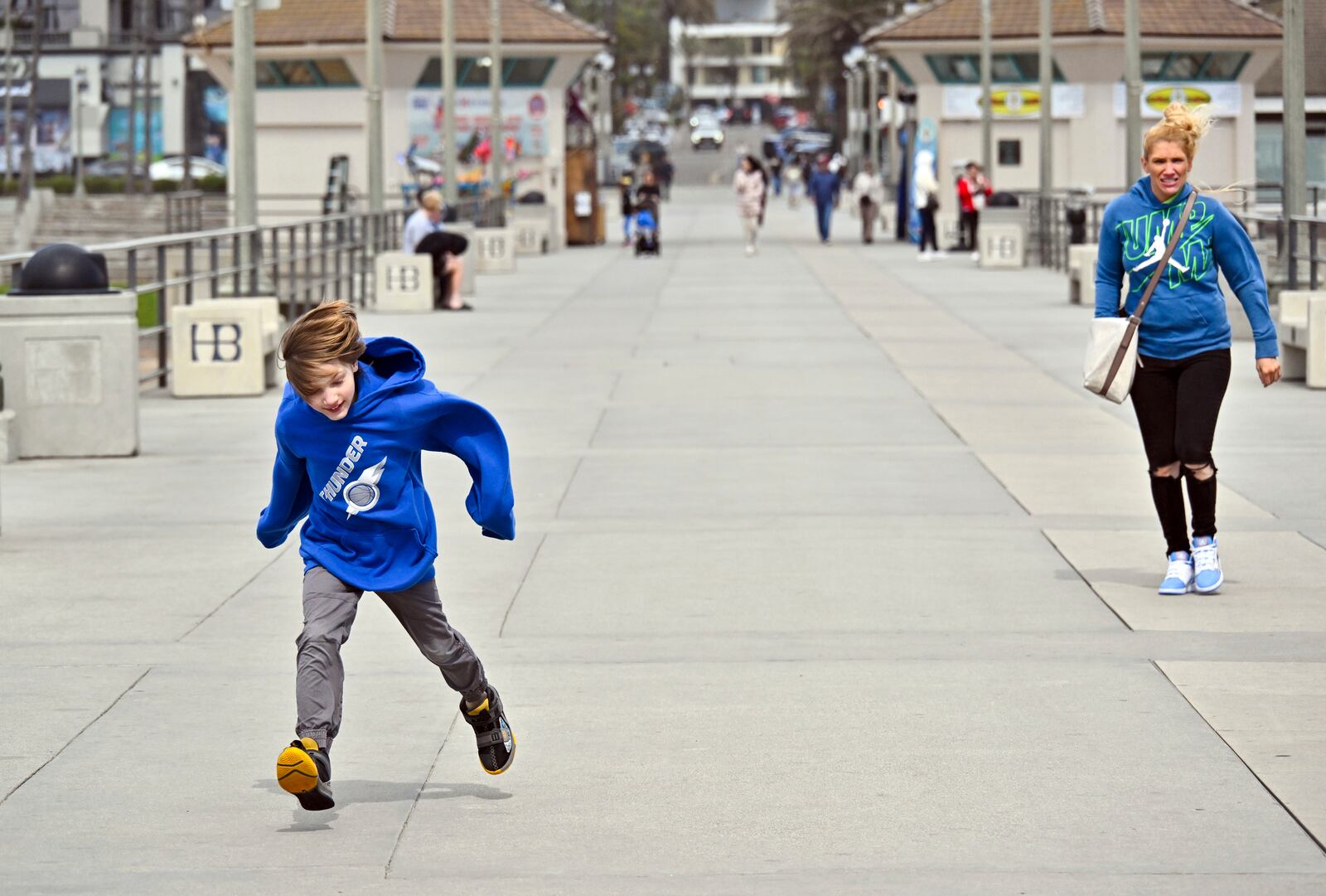 Hudson Kammarcal, 8, runs in the wind as his mother, Heidi Kammarcal, of Coeur d'Alene, Idaho, tries to keep up on the pier in Huntington Beach, Calif., Thursday, March 13, 2025, after strong storms moved through the region overnight. (Jeff Gritchen/The Orange County Register via AP)