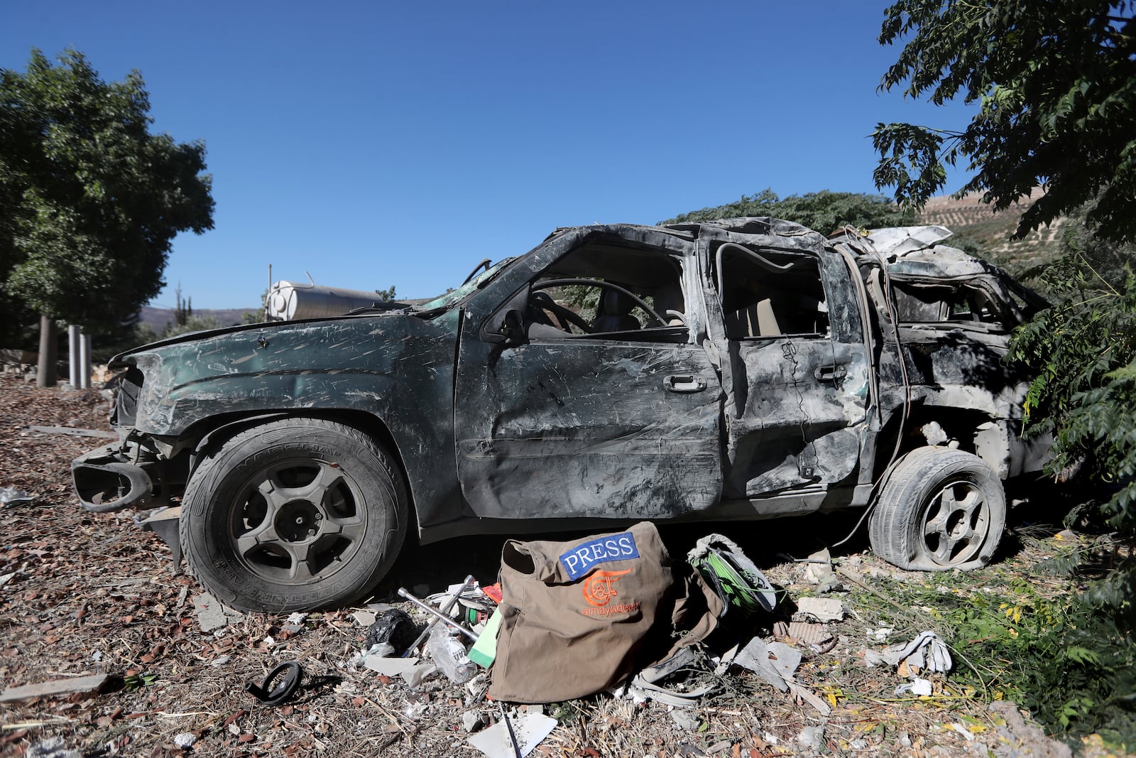 Journalists' items on the ground next to a destroyed vehicle, at the site where an Israeli airstrike hit a compound housing journalists, killing three media staffers from two different news agencies according to Lebanon's state-run National News Agency, in Hasbaya village, southeast Lebanon, Friday, Oct. 25, 2024. (AP Photo/Mohammed Zaatari)